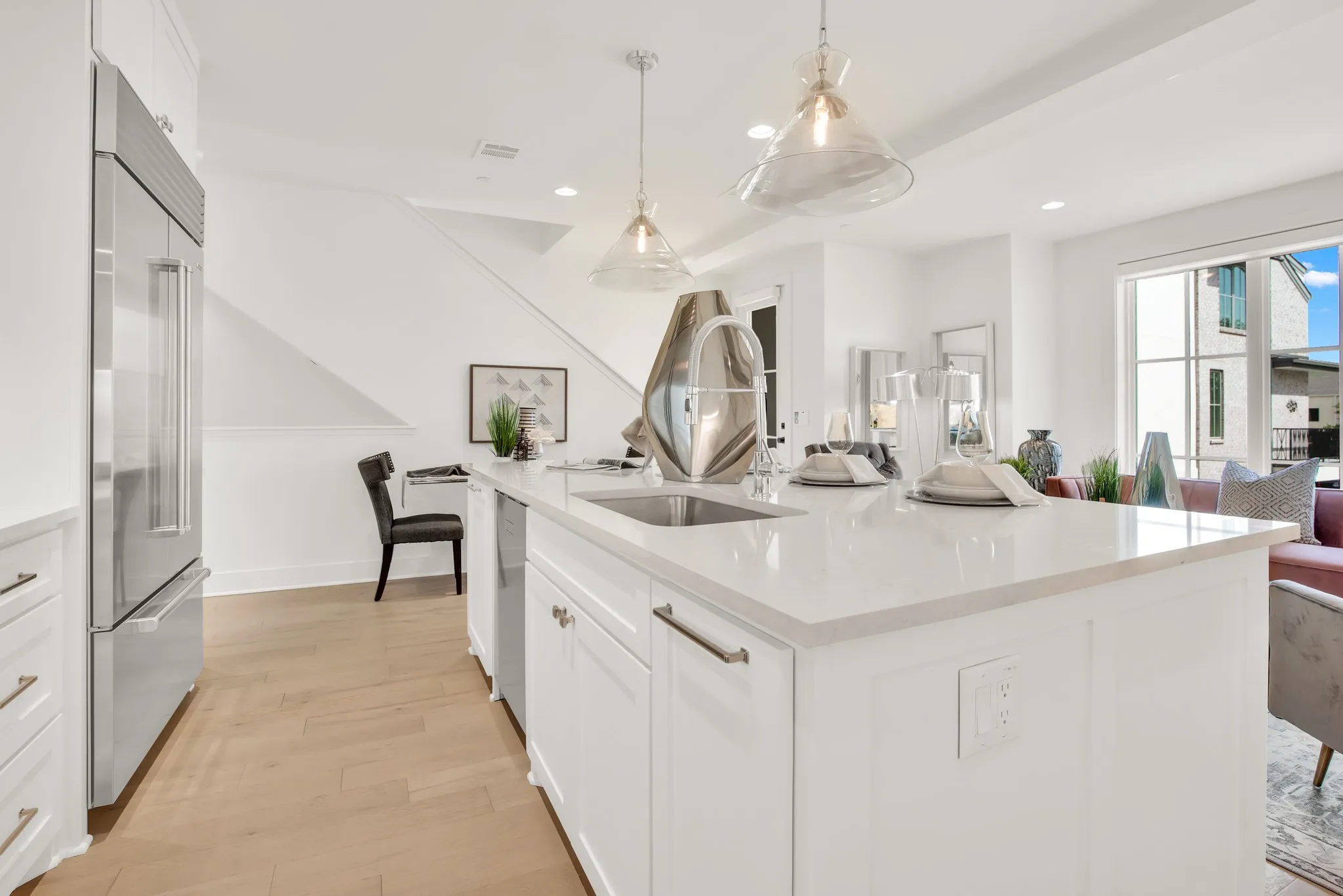 Kitchen with white cabinets, light stone counters, a large island, decorative light fixtures, and stainless steel appliances