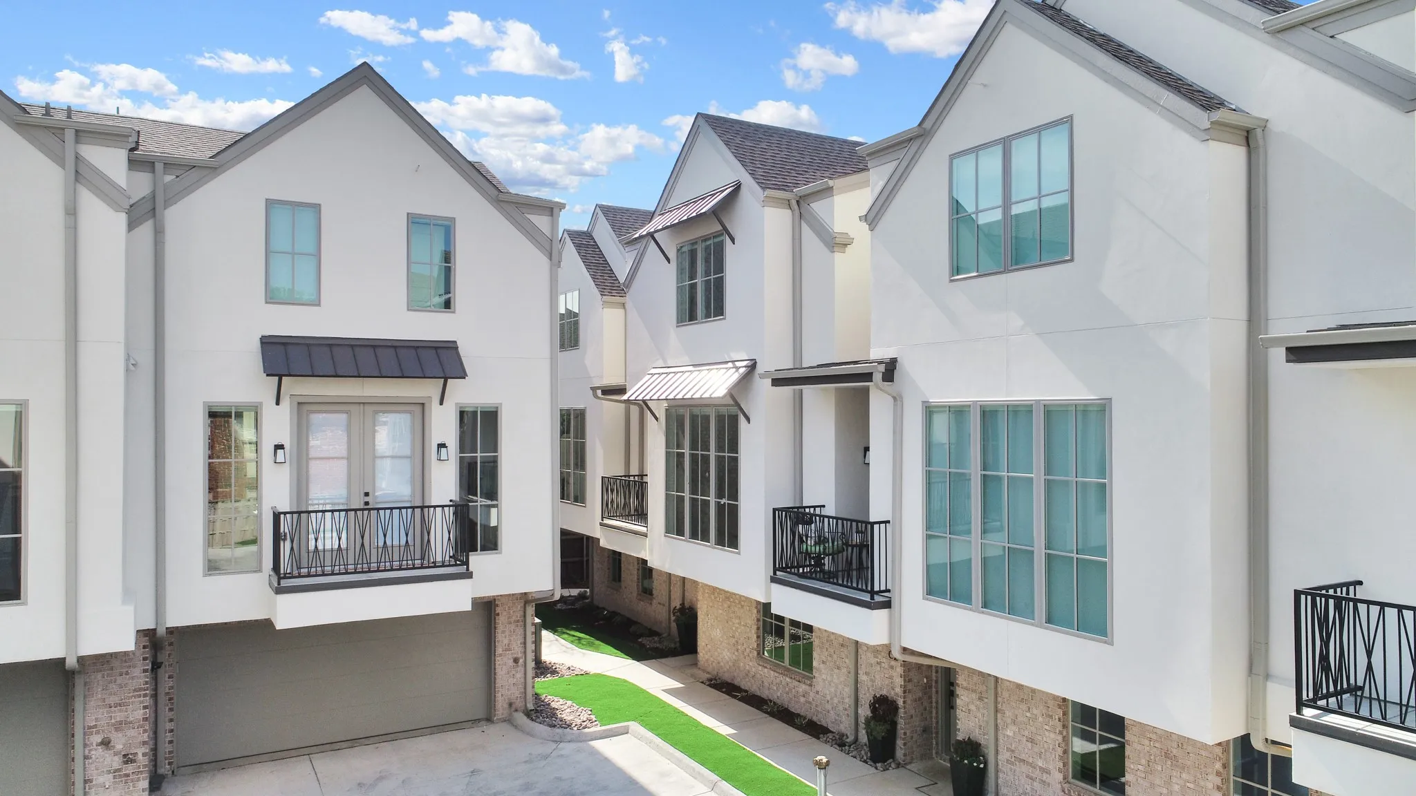 View of front of home featuring brick siding, a standing seam roof, a residential view, a metal roof, and a balcony