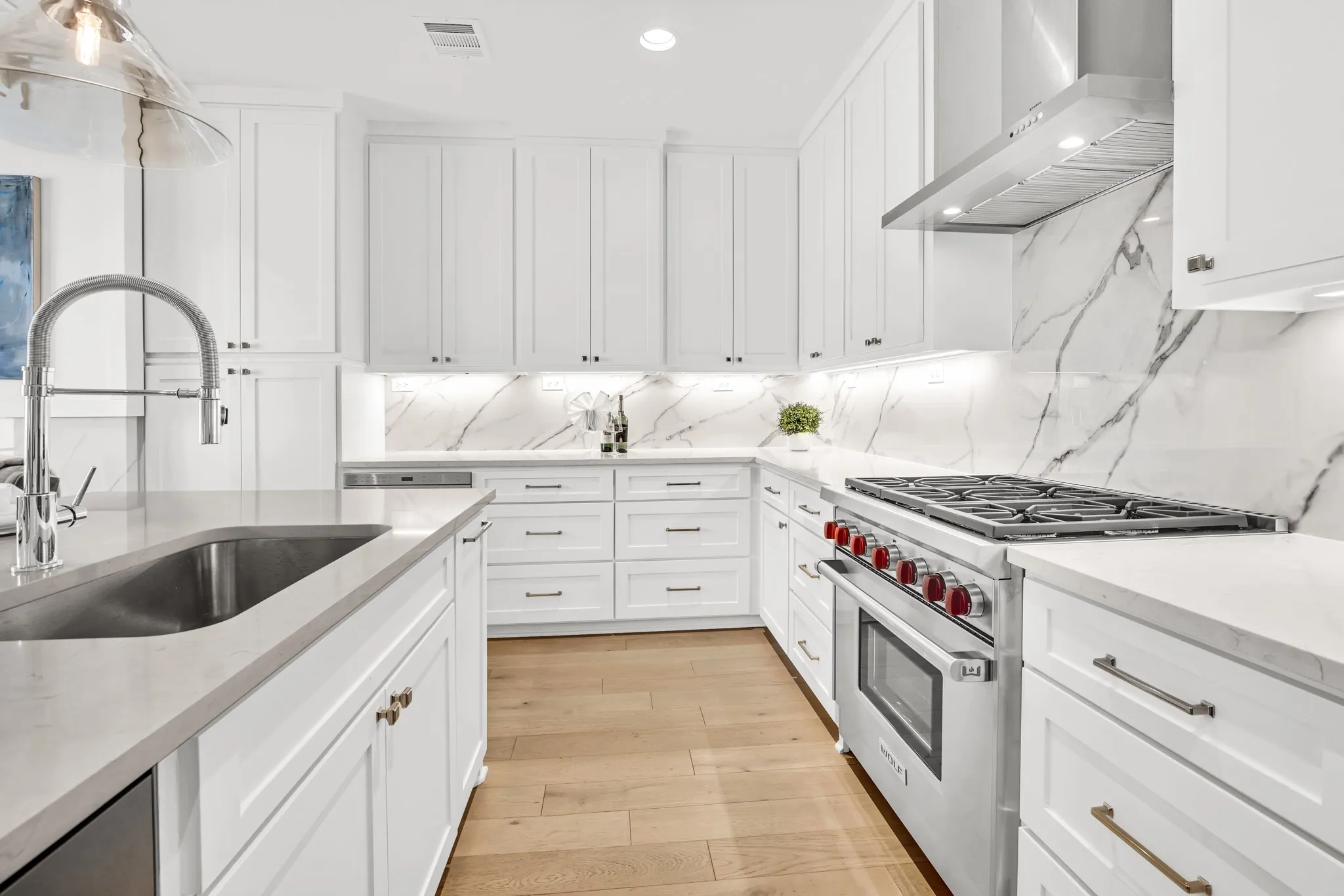 Kitchen with designer range, wall chimney range hood, white cabinetry, decorative backsplash, and light stone counters
