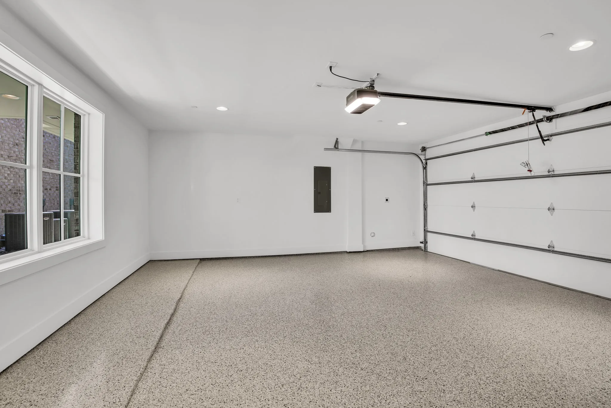 Garage with electric panel, a garage door opener, and recessed lighting