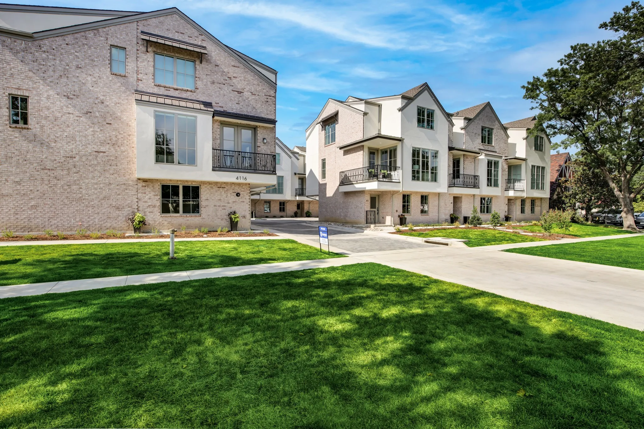 View of front facade featuring brick siding, a balcony, a residential view, a front yard, and driveway