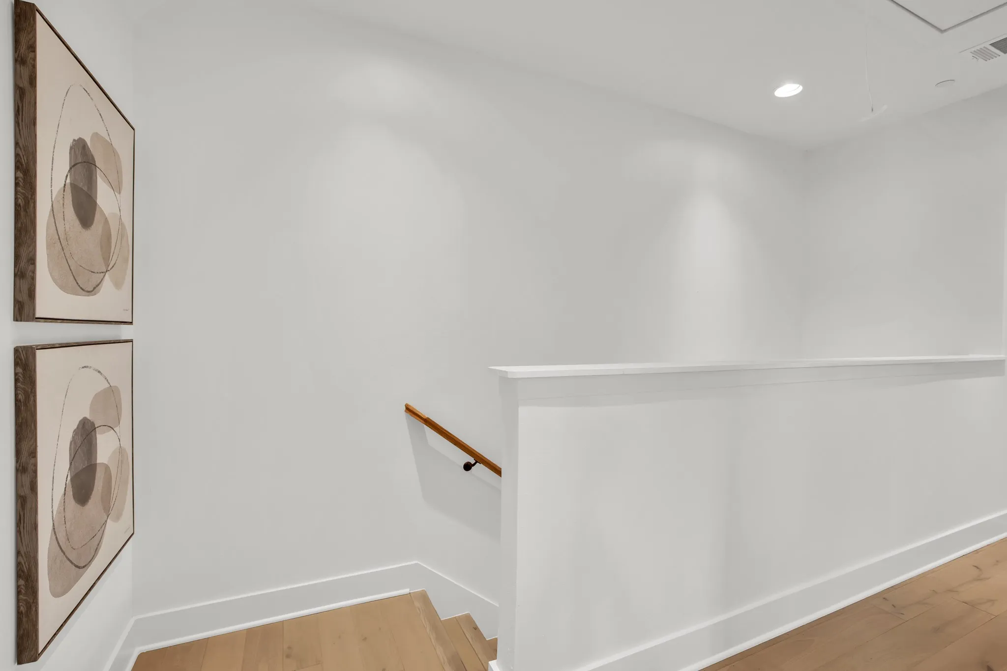 Washroom with wood finished floors, recessed lighting, stacked washer and clothes dryer, and attic access