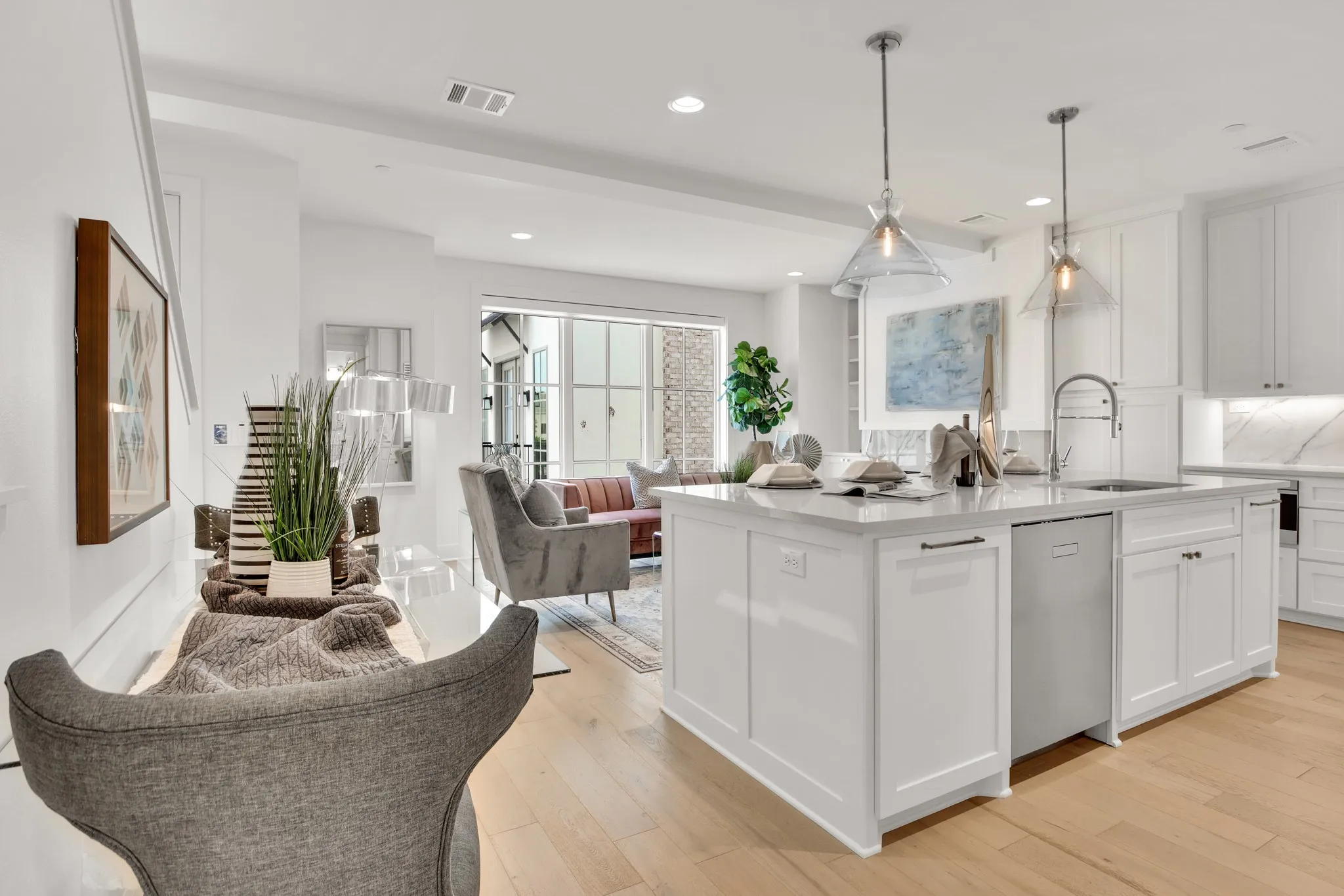 Kitchen featuring light stone counters, white cabinets, an island with sink, open floor plan, and recessed lighting