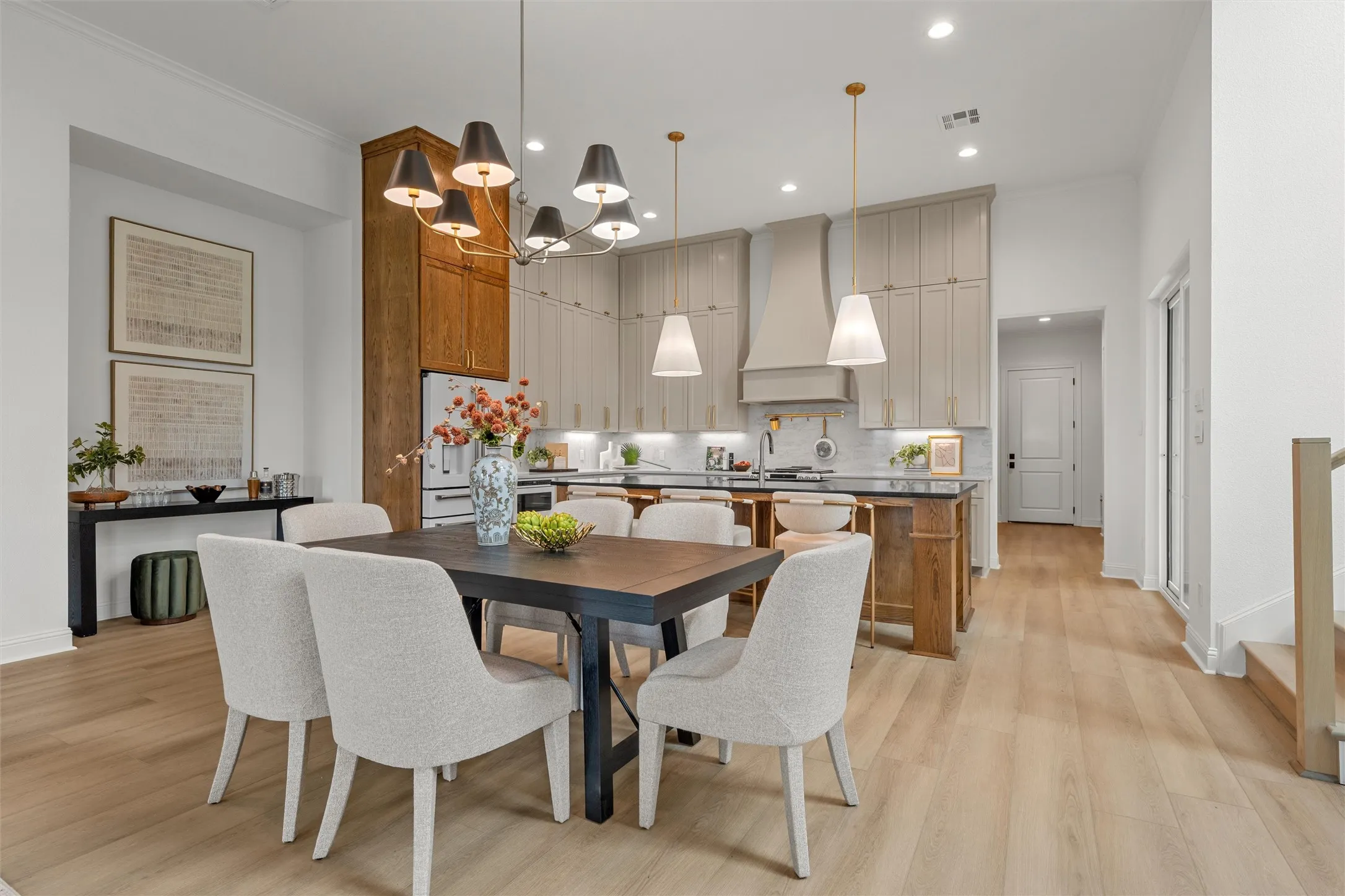Open-concept living space with light wood-finish flooring, a contemporary chandelier, and recessed lighting