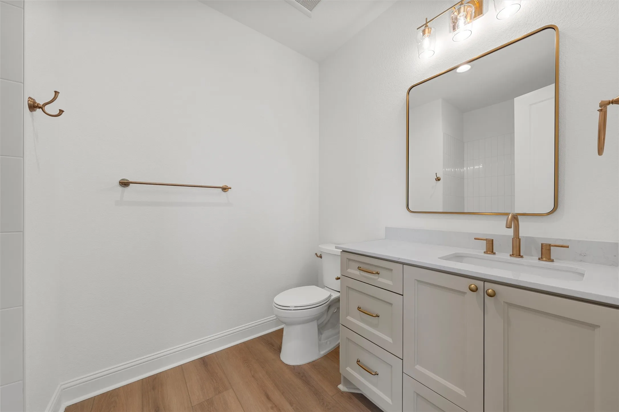 Vanity with a light-toned countertop, under-mount sink, and brass fixtures
