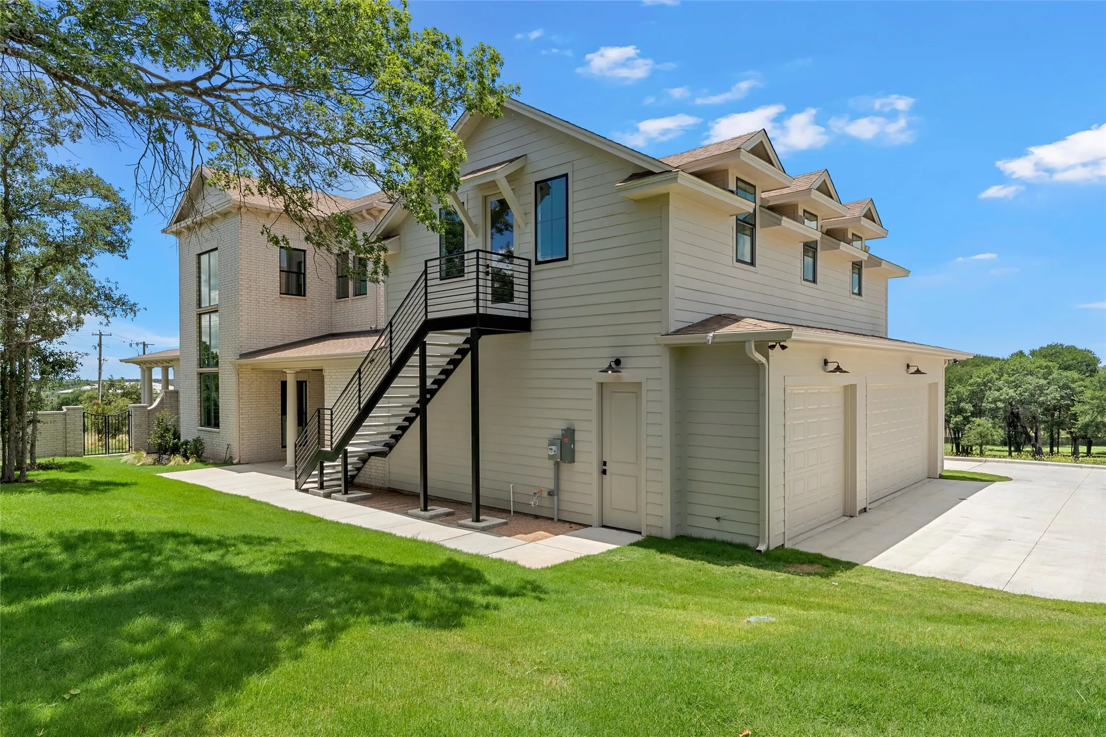 Contemporary exterior featuring a two-car garage, dormer windows, and an external staircase with metal railings