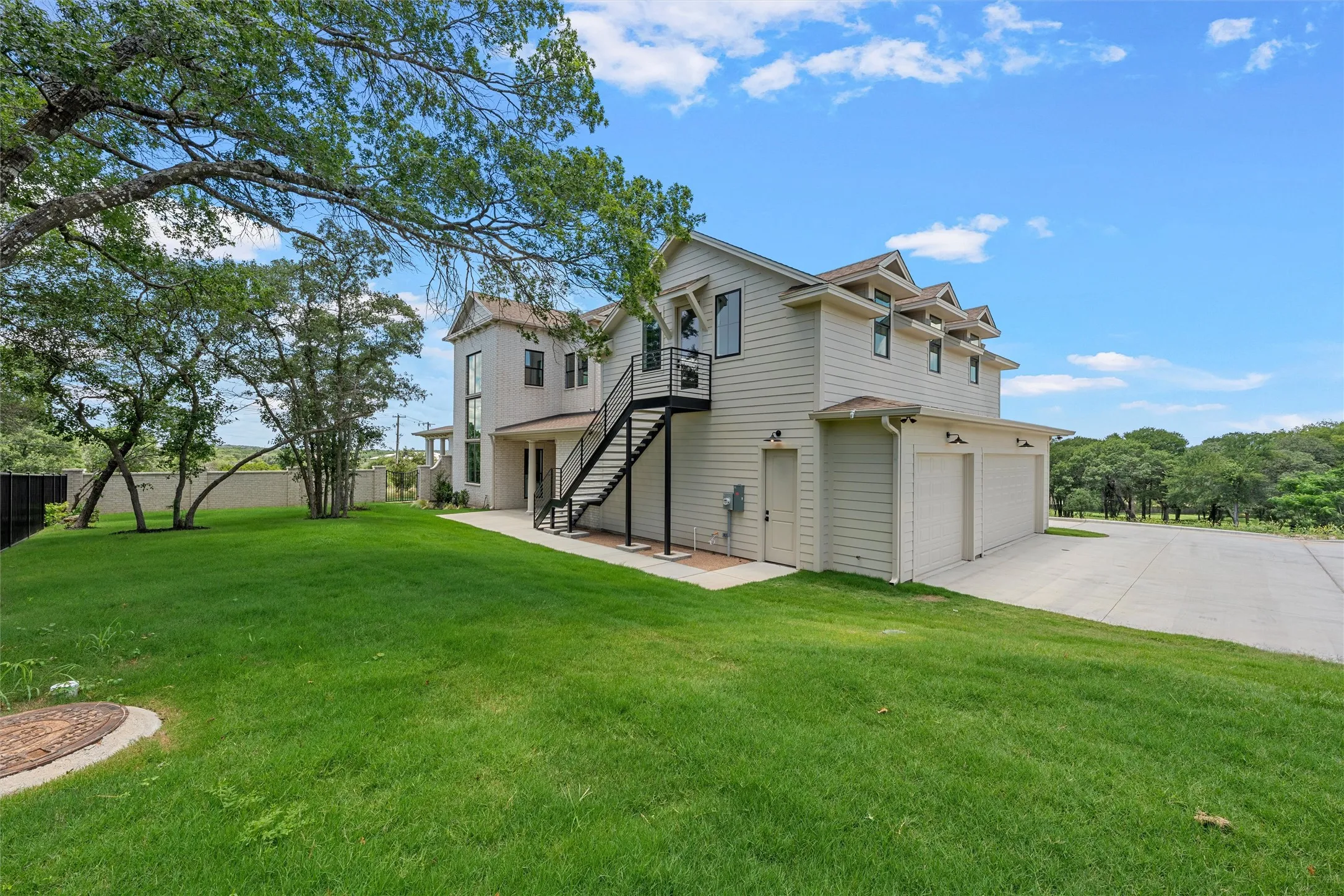 Two-story residence with light-colored siding, a multi-car garage, and an exterior staircase with a black railing