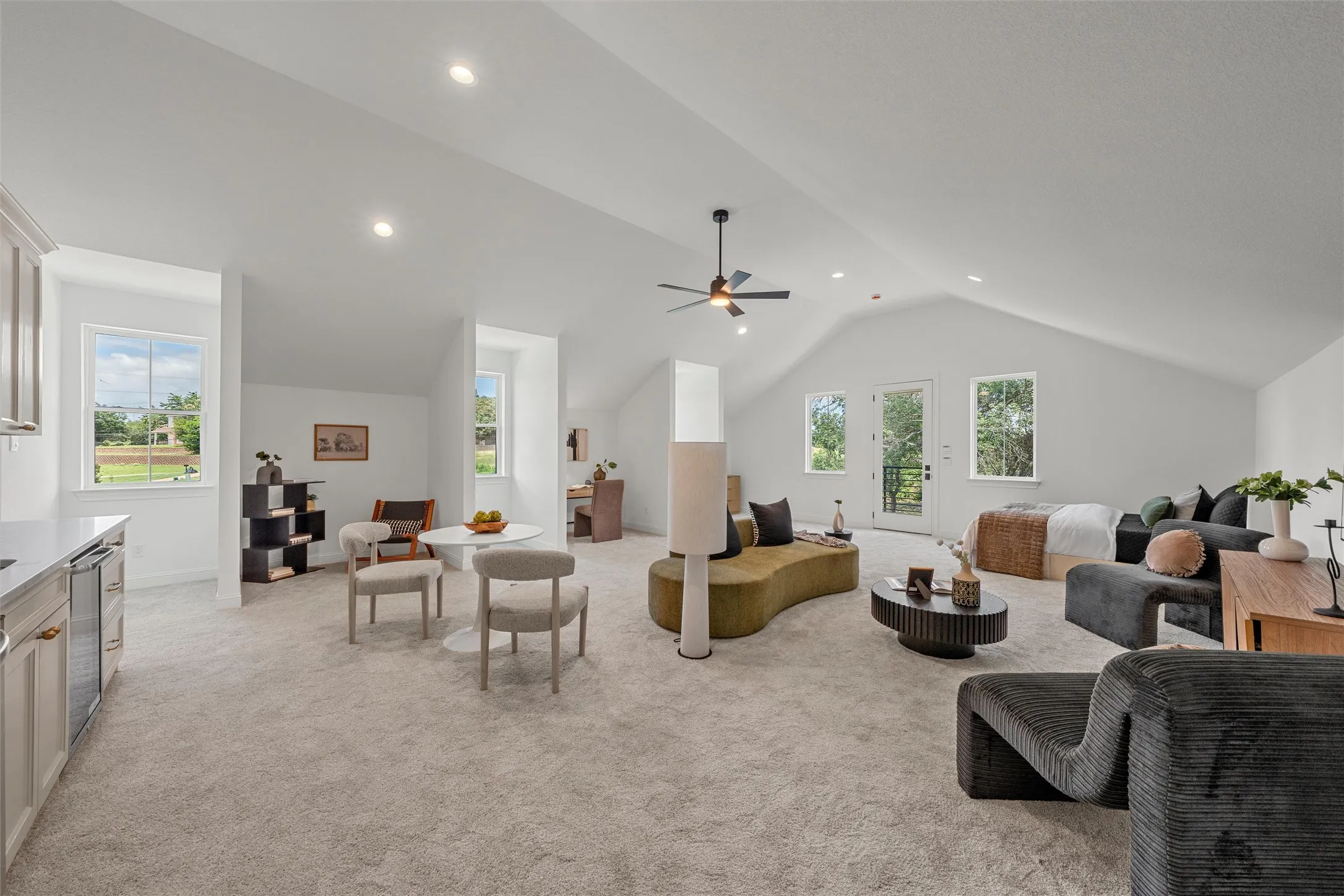 Spacious room with vaulted ceilings, recessed lighting, and light-toned carpeting