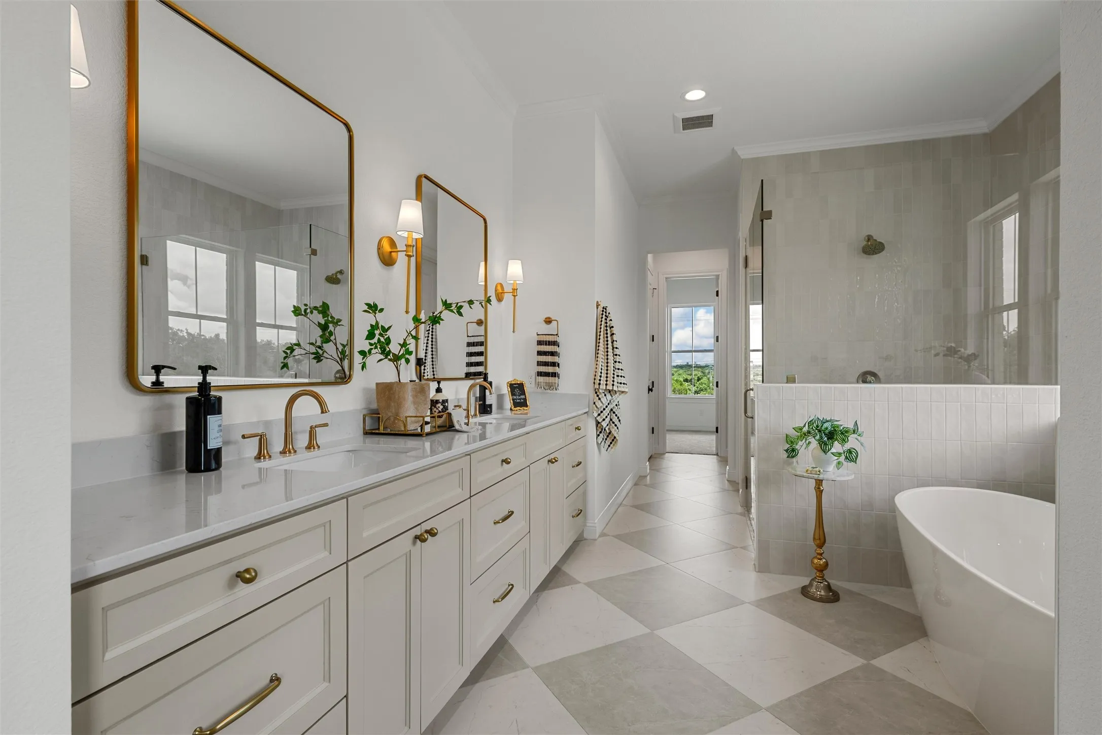 Dual vanity with white shaker cabinetry, gold-finish hardware, and a light-toned countertop