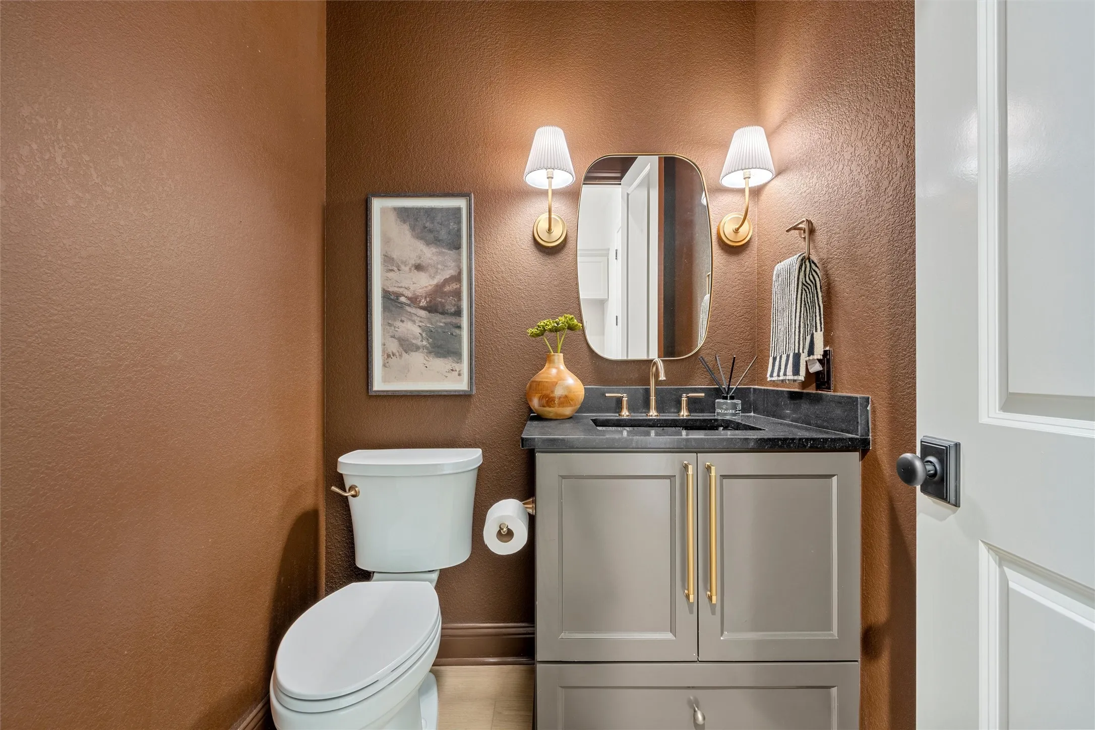Gray vanity with golden hardware, black countertop, and gold-finish faucet