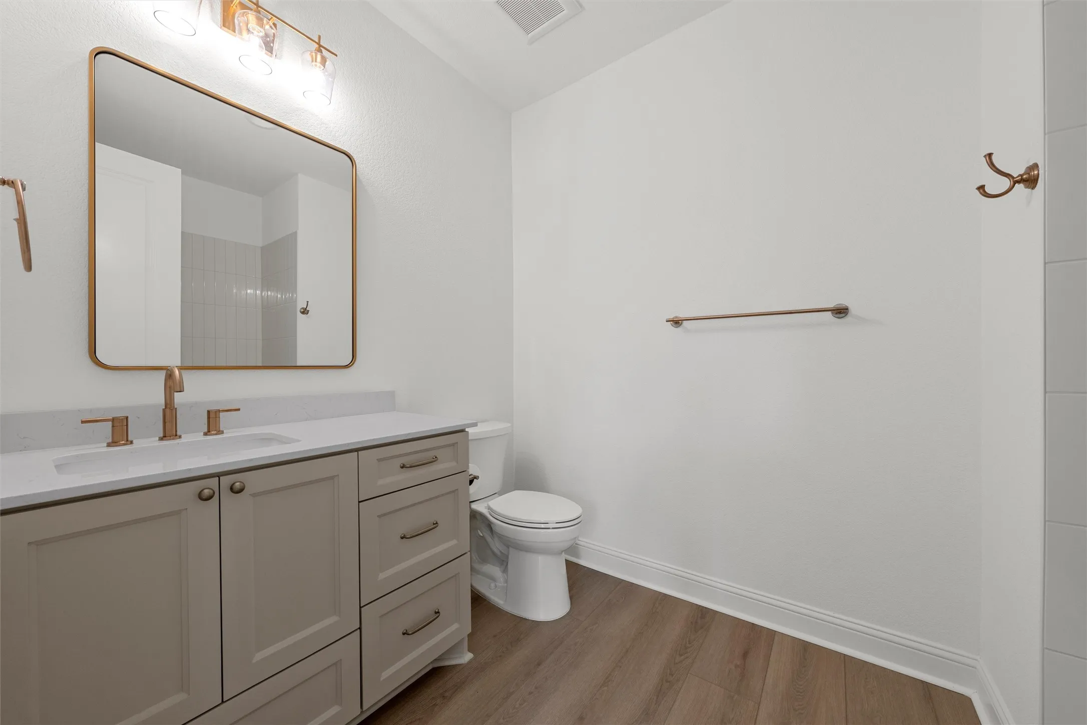Vanity with a light countertop, integrated sink, and modern bronze faucet