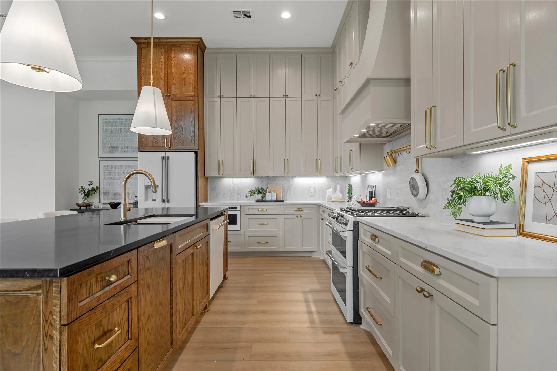 Gourmet kitchen with wood-finish flooring, two-tone cabinetry, stone countertops, and a full suite of stainless steel appliances