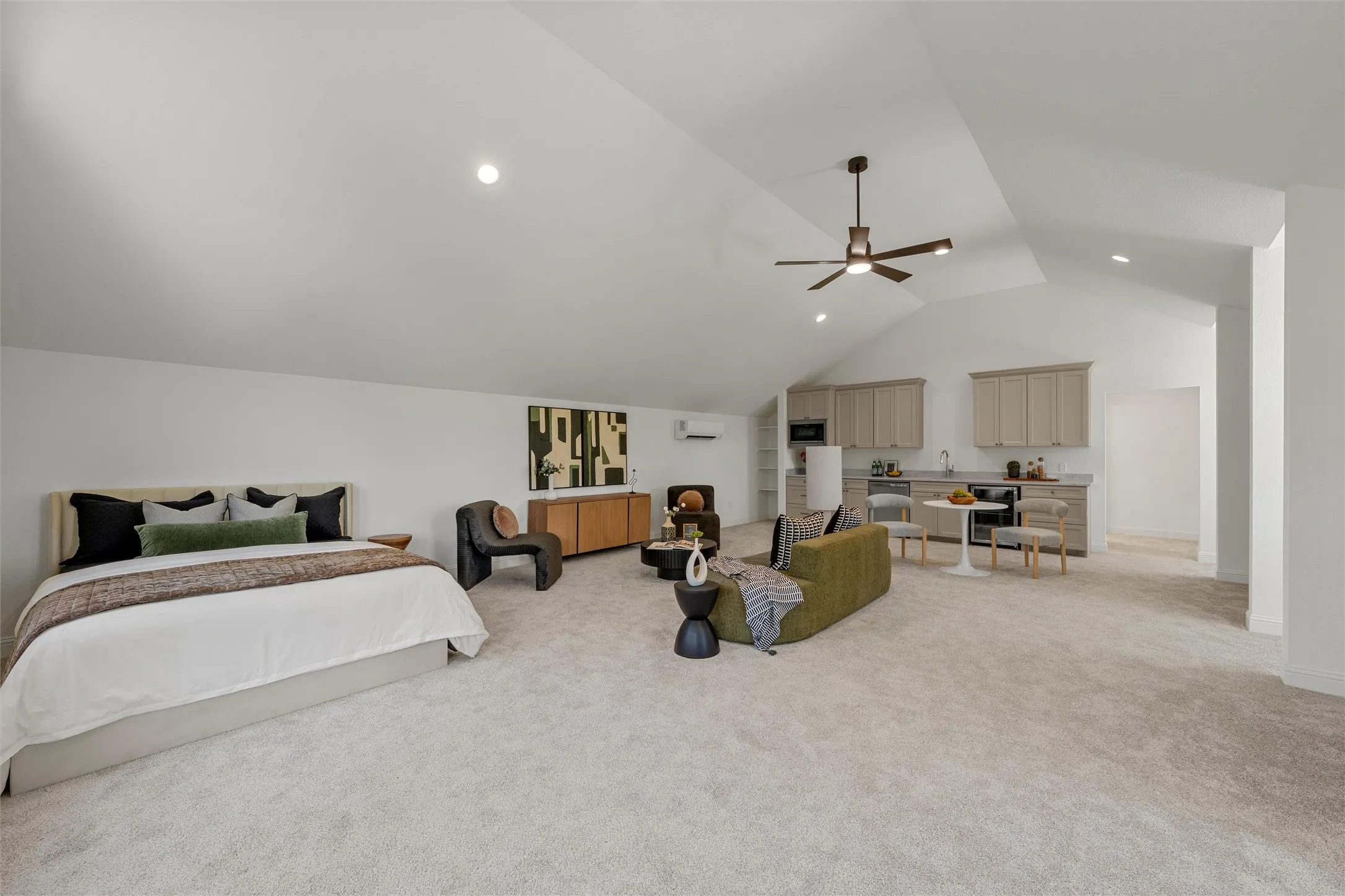 Vaulted ceilings with recessed lighting, integrated ceiling fan, light-toned carpeting, built-in cabinetry with sink, and a mini-split HVAC unit