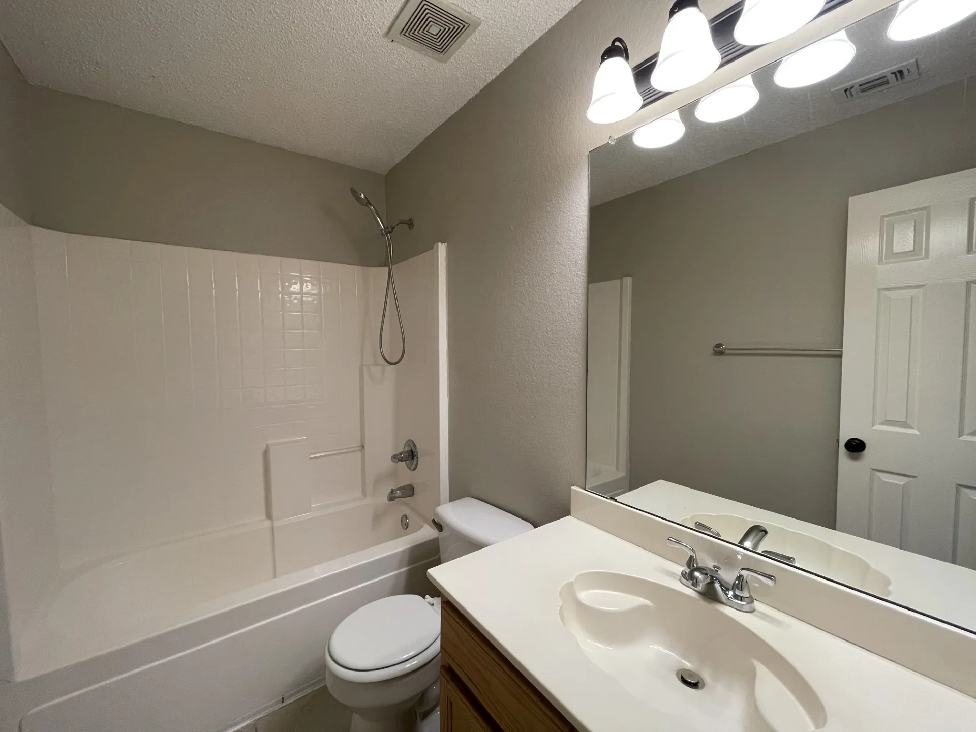 Full bath featuring a textured ceiling, shower / bathtub combination, and vanity