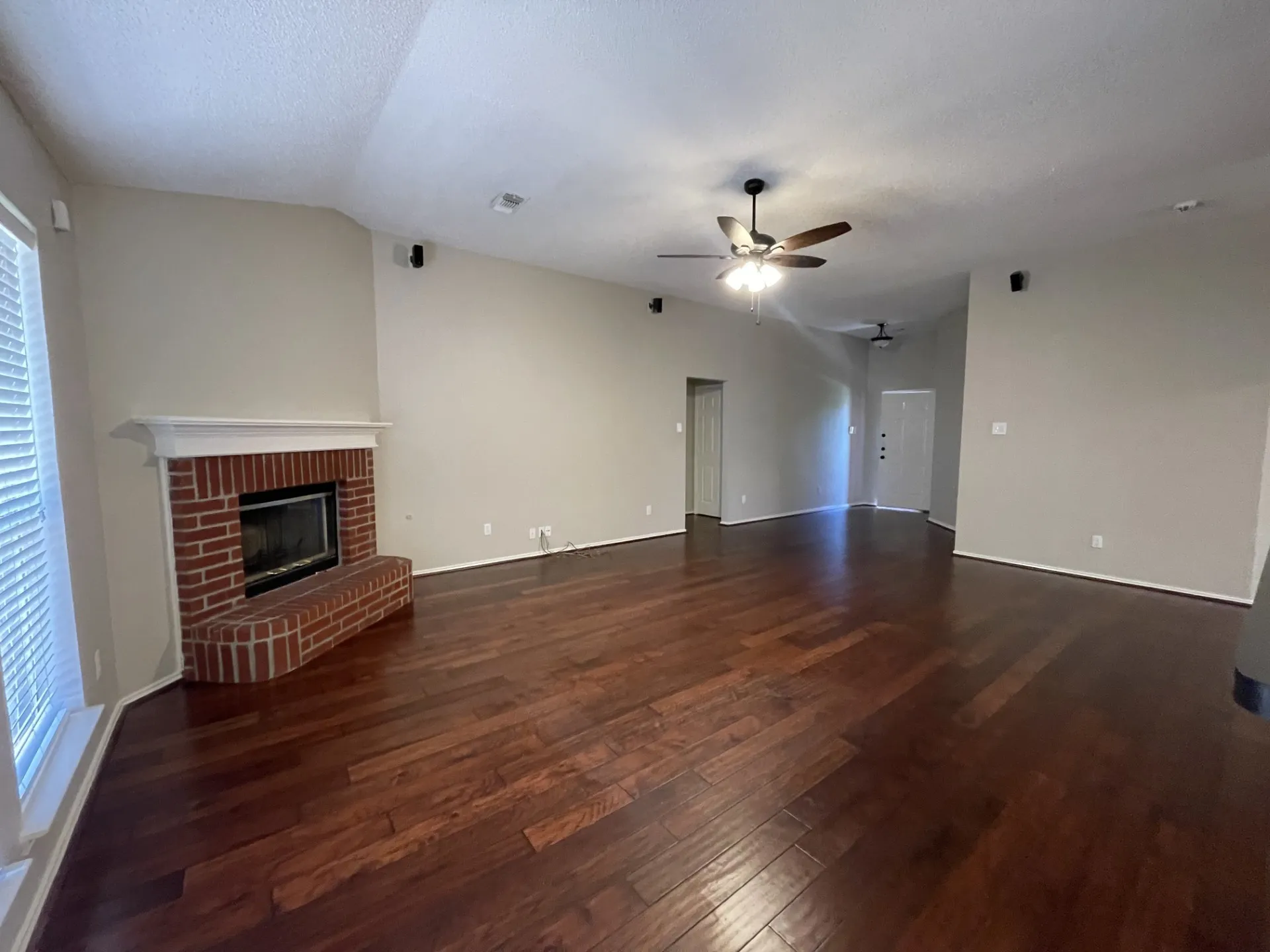 Unfurnished living room with hardwood / wood-style floors, a ceiling fan, a brick fireplace, and lofted ceiling