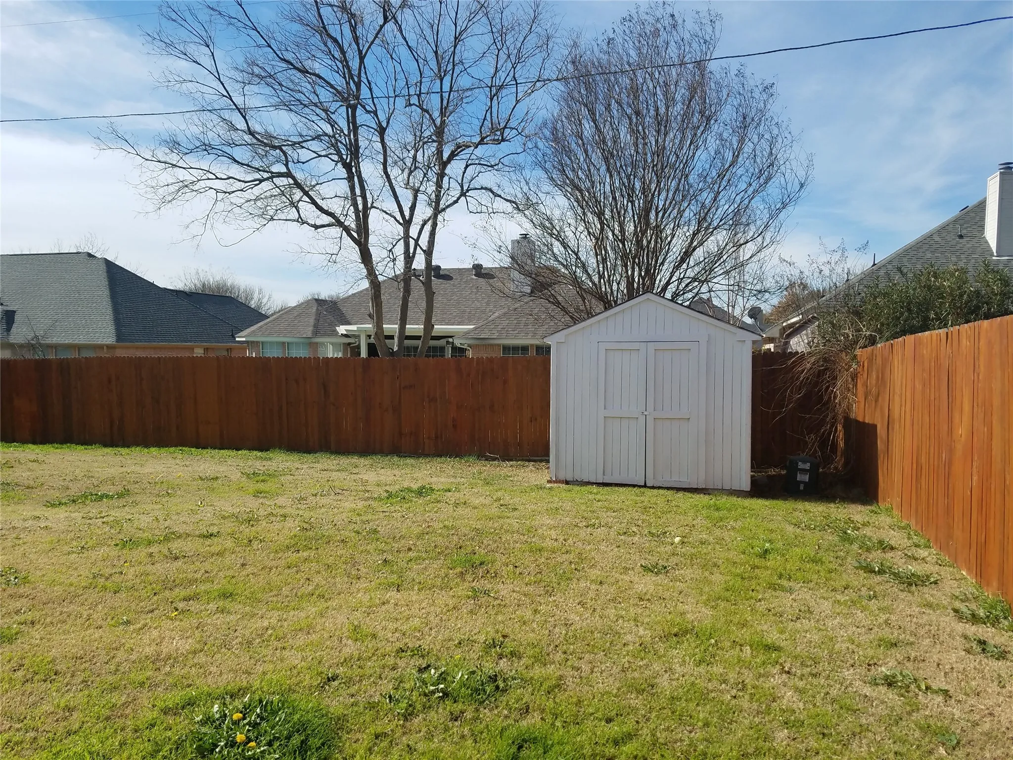 Fenced backyard featuring a storage shed