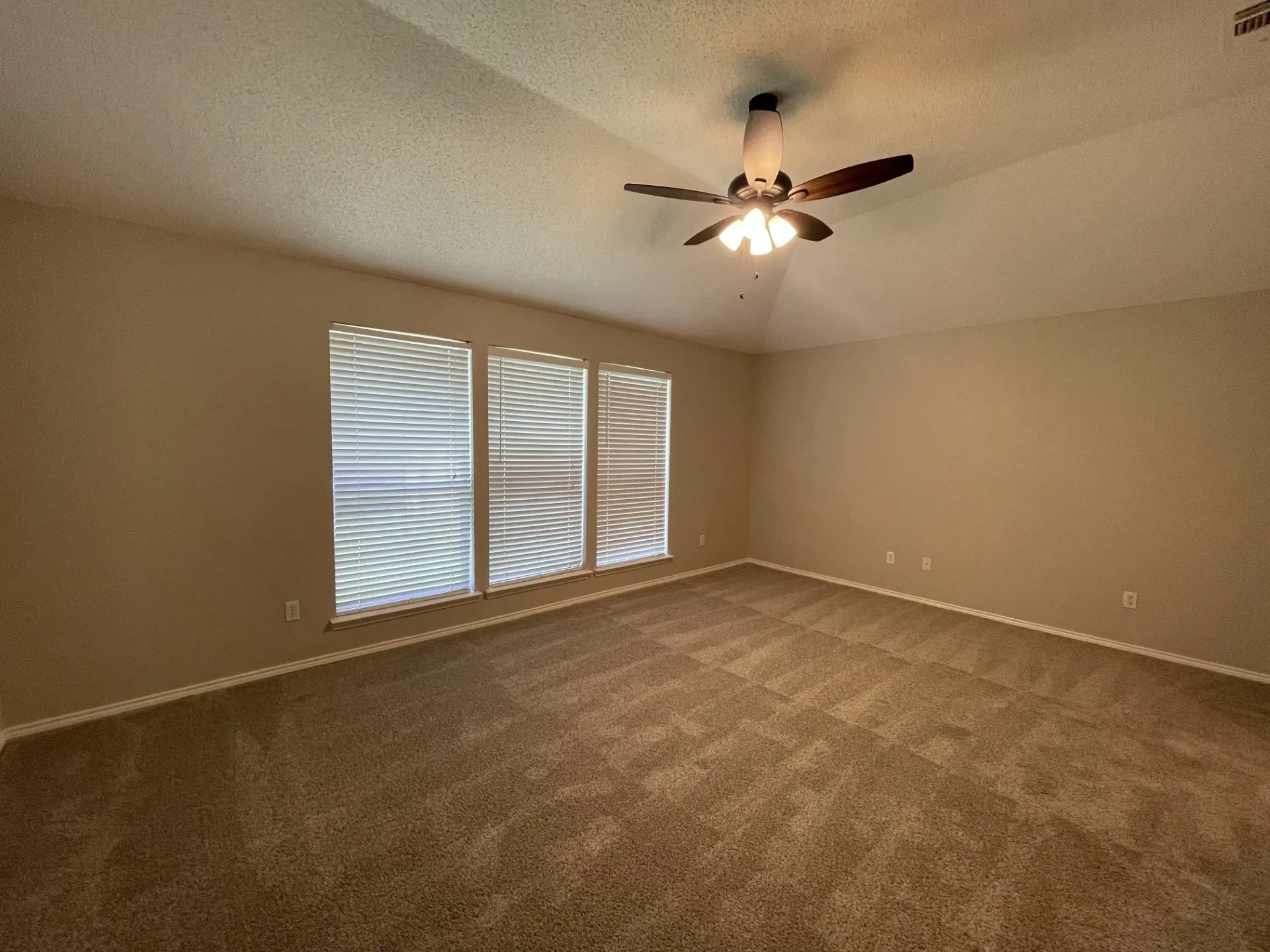 Empty room with dark carpet, a ceiling fan, a textured ceiling, and vaulted ceiling