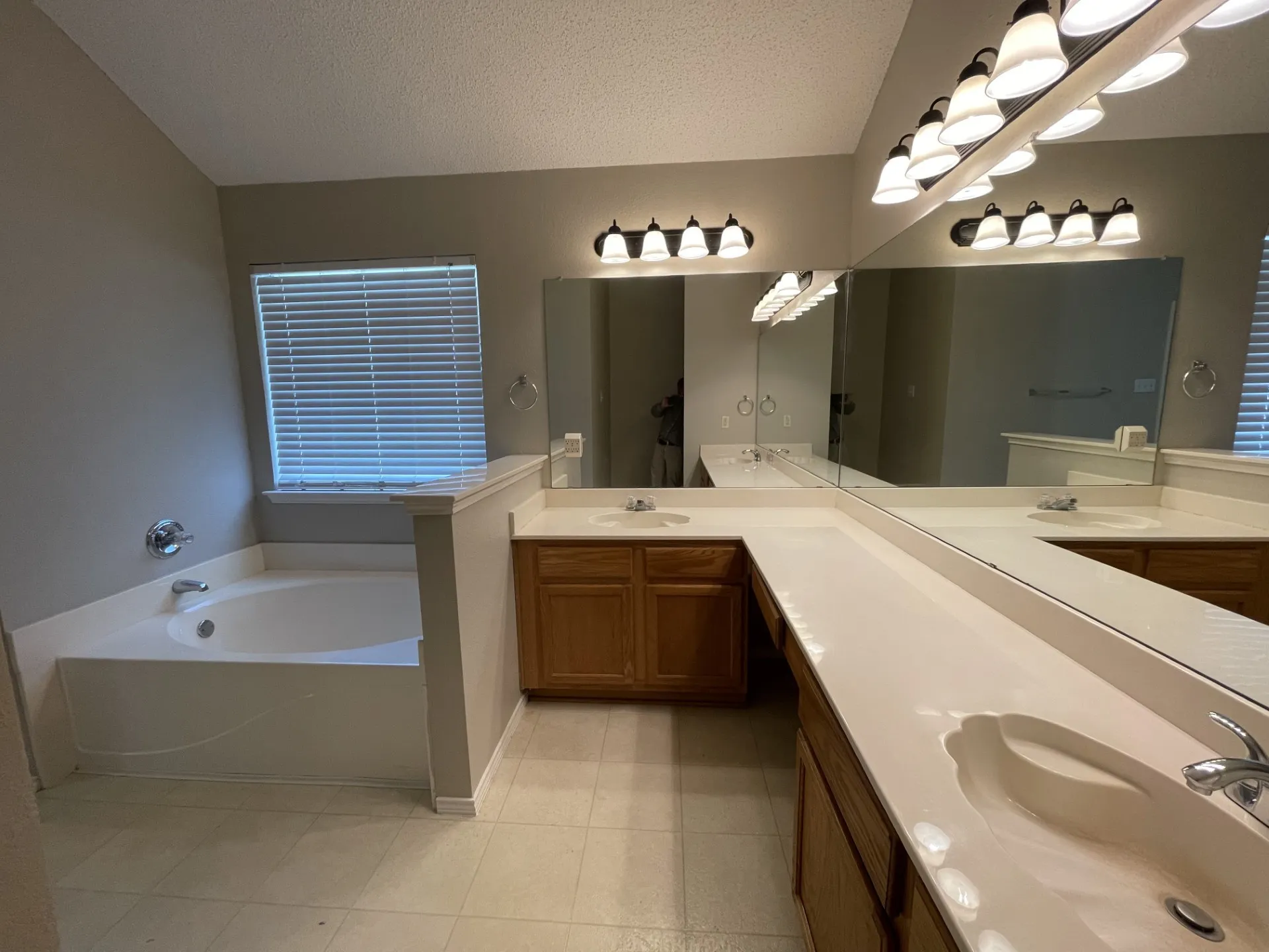 Bathroom with double vanity, a bath, tile patterned flooring, and a textured ceiling
