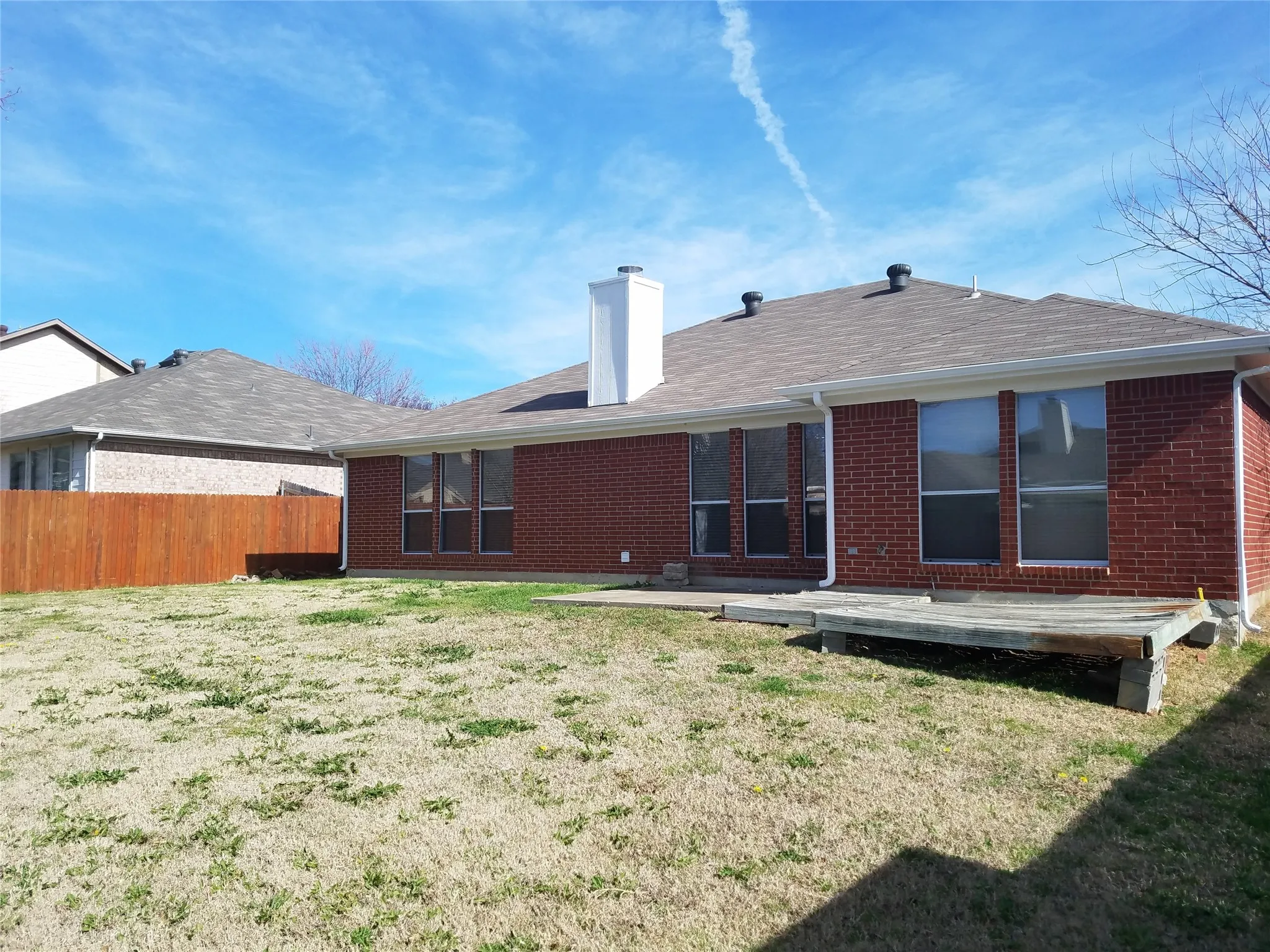 Back of property featuring brick siding, a chimney, and a shingled roof