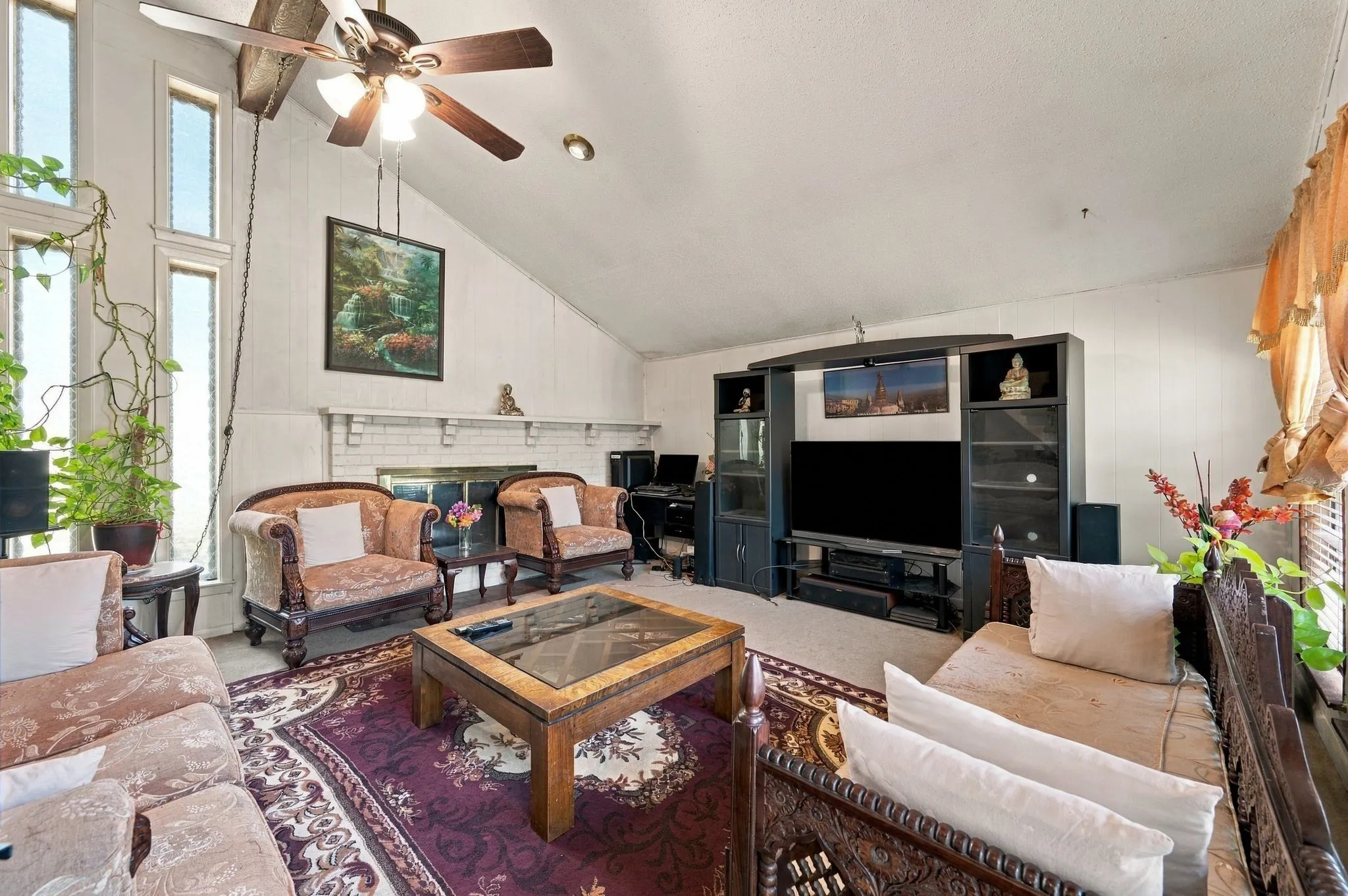 Living room located immediately to the left upon entry from the front door with ceiling fan, and lots of natural light, and half-wall brick fireplace with gas starter.