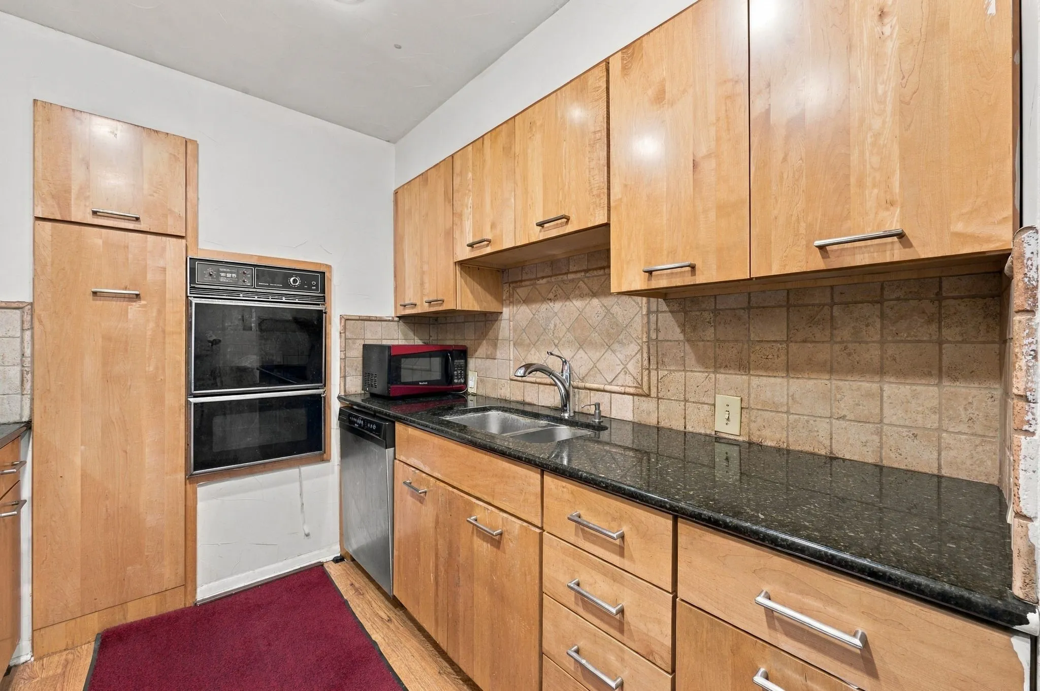 Updated kitchen with granite countertops, ample cabinetry, backsplash, stainless steel refrigerator, dishwasher, microwave.