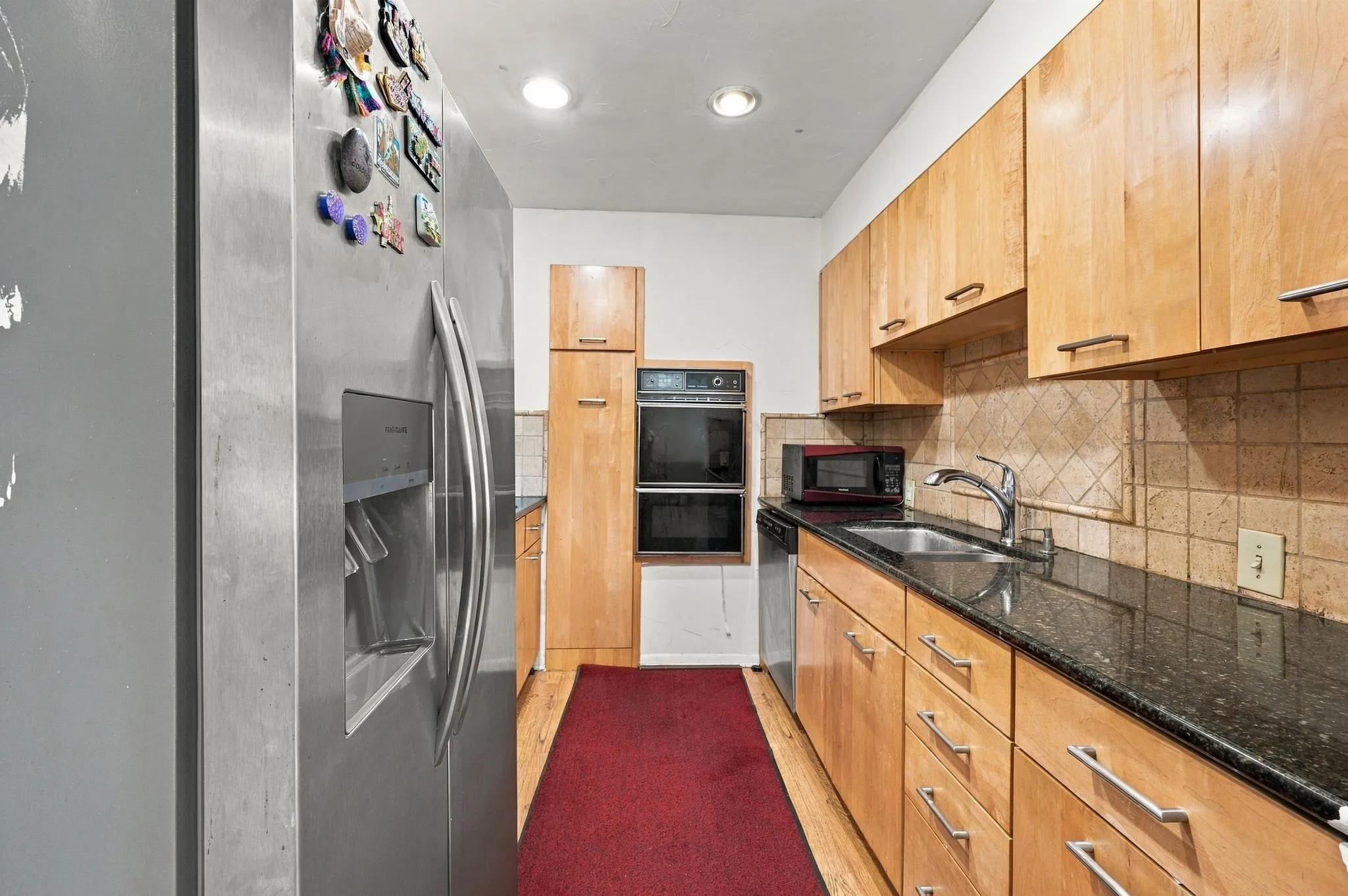 Updated kitchen with granite countertops, ample cabinetry, backsplash, stainless steel refrigerator, dishwasher, microwave.