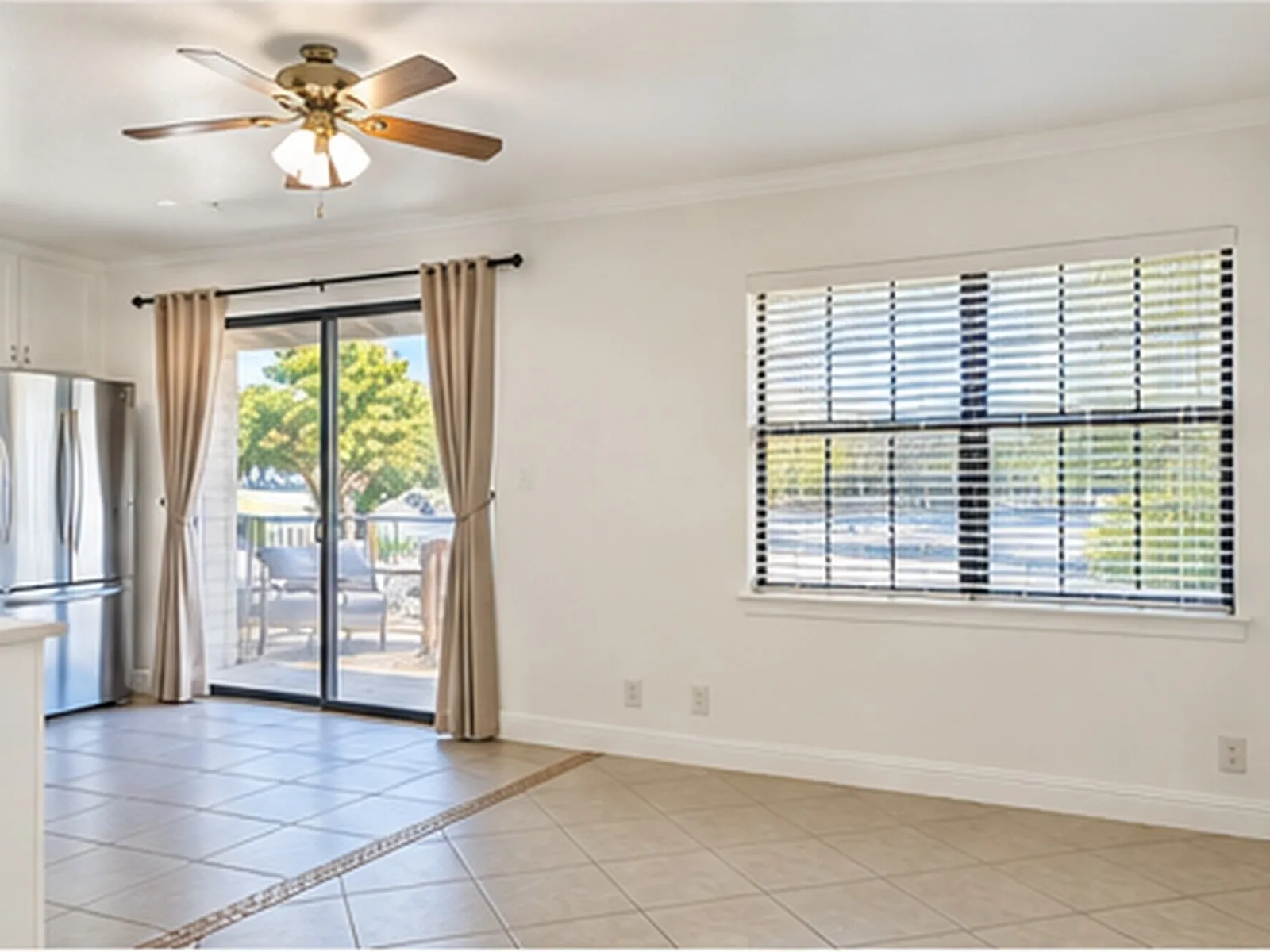 Tile flooring with decorative inlay, sliding glass door with outdoor patio, ceiling fan with integrated lighting, and a large window with blinds