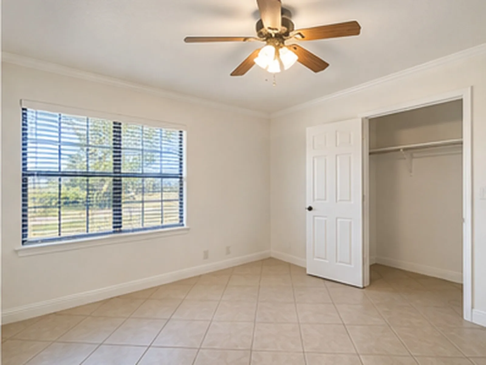 Ceiling fan with light kit, crown molding, tile flooring, window with blinds, and a built-in closet with shelving