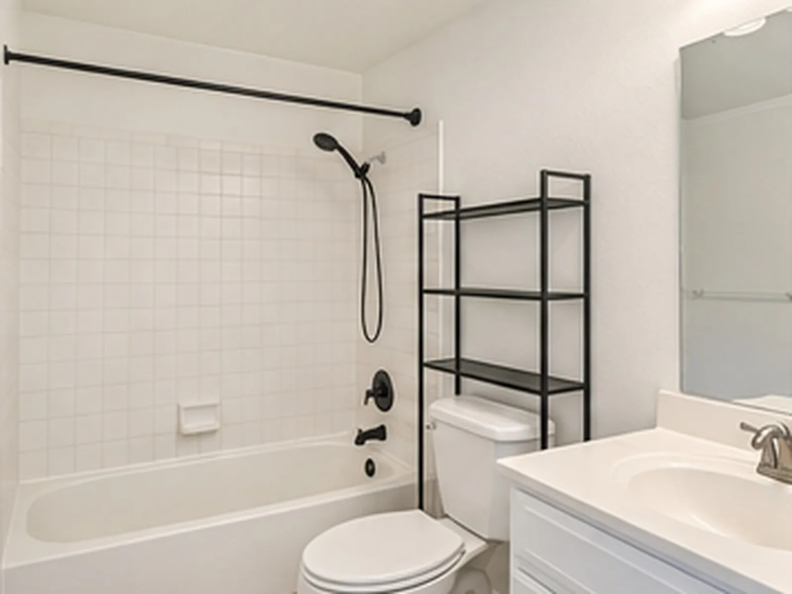 Bathtub with white square tile surround and matte black fixtures