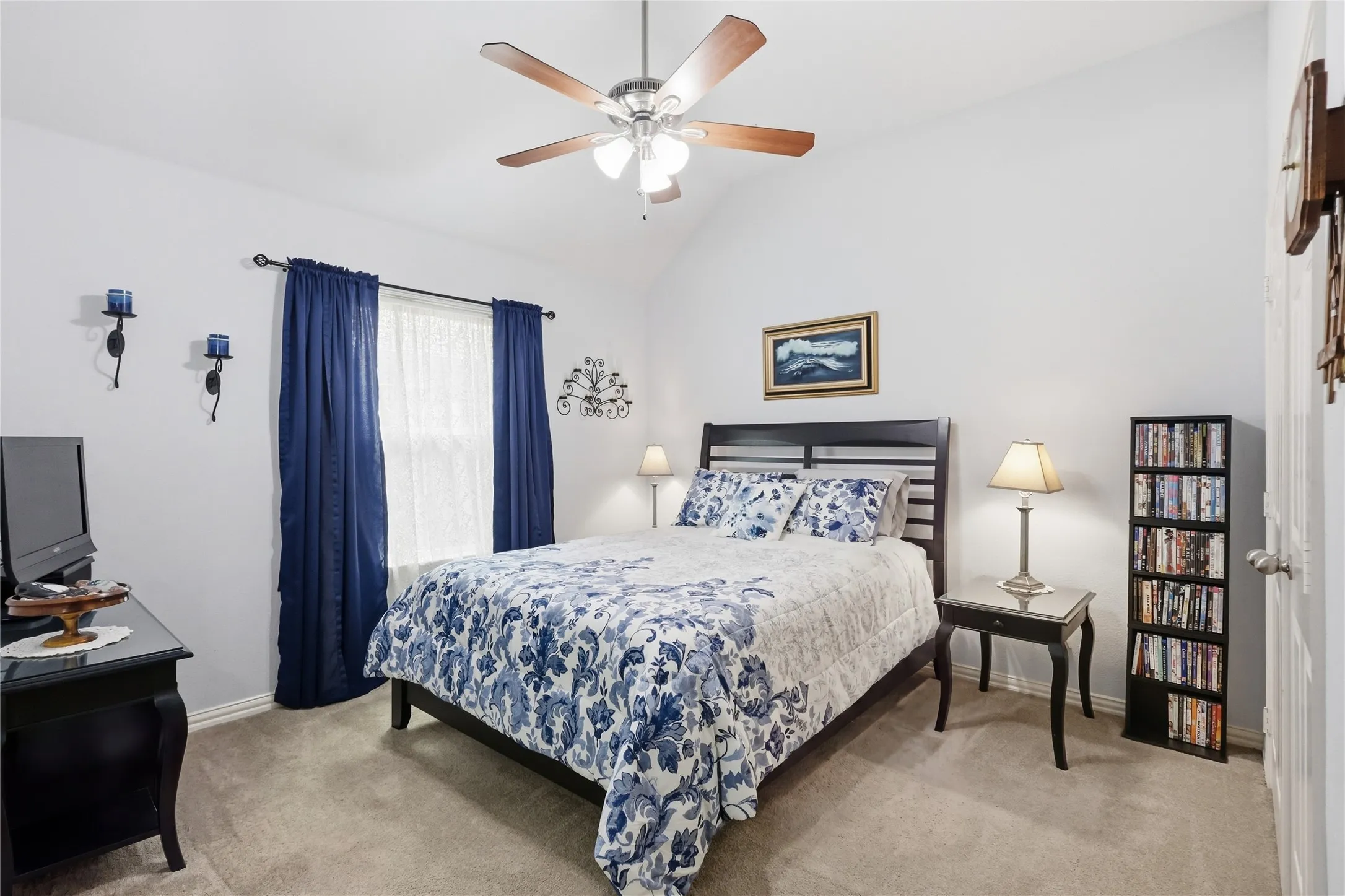 Vaulted ceiling with a ceiling fan, window with curtain rods, sconce lighting, and carpet flooring