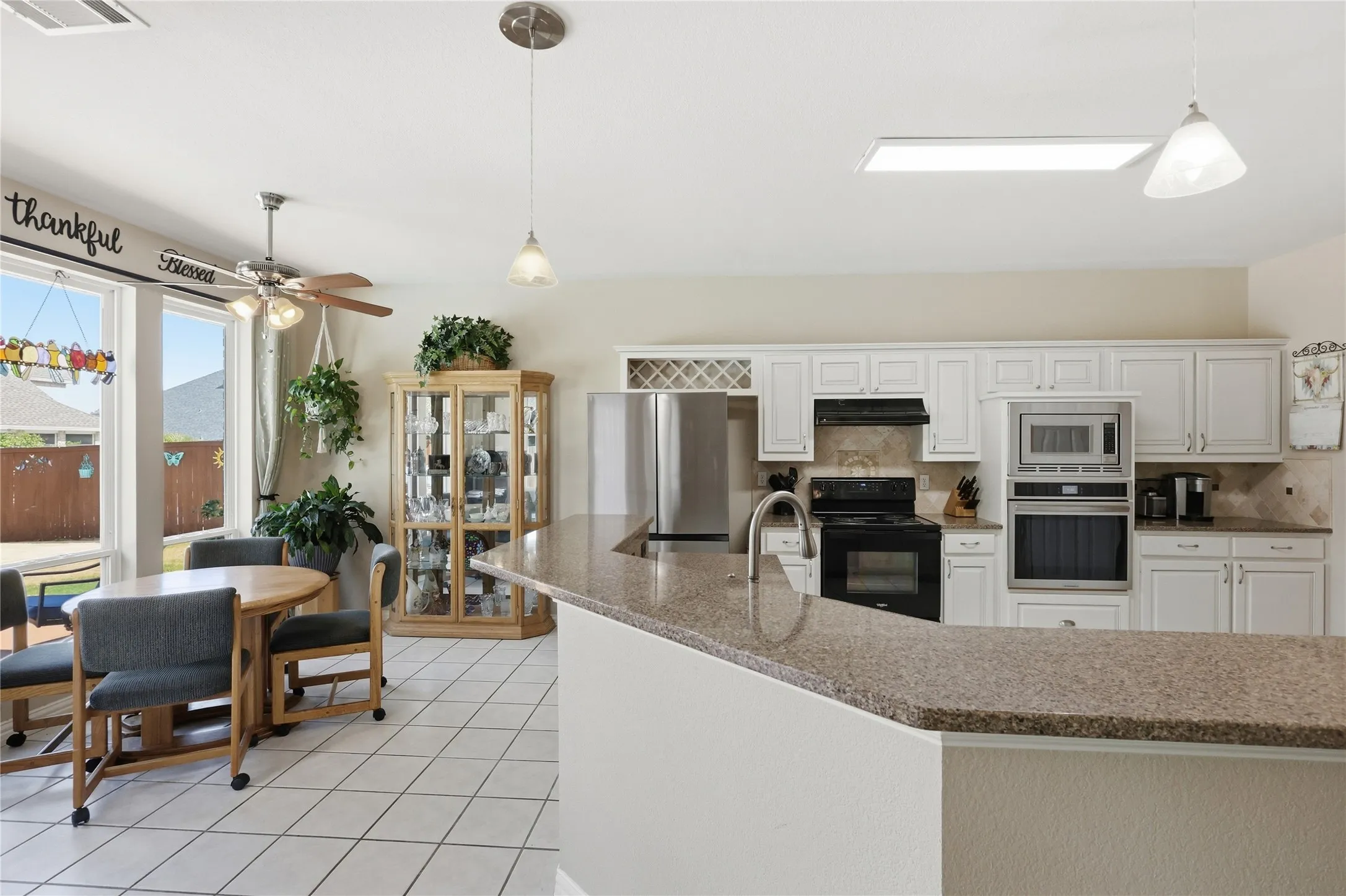 Kitchen featuring white cabinetry, stone-finish countertops, stainless steel appliances, and tile flooring