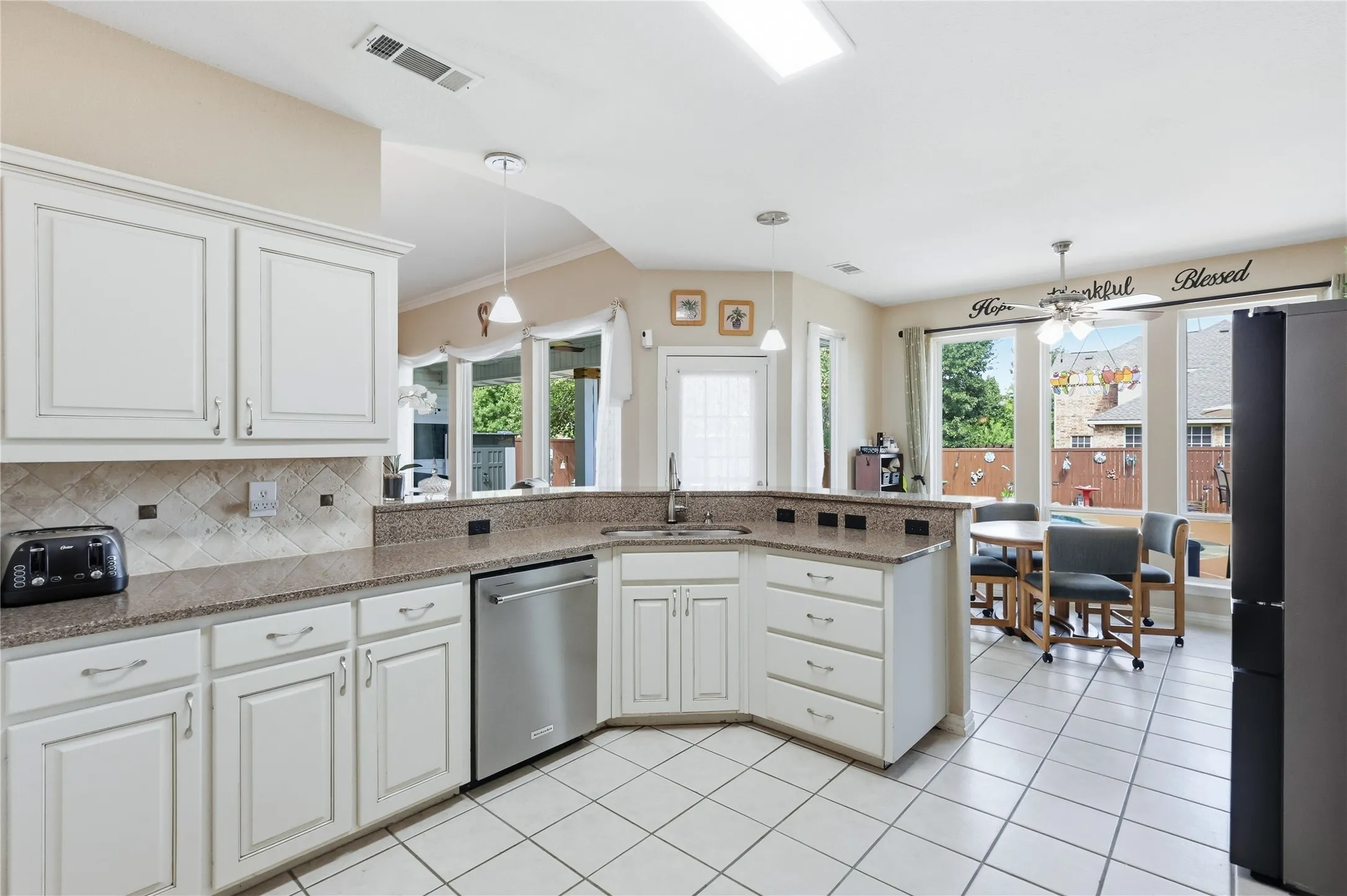 White cabinetry with brushed nickel pulls, granite-finish countertops, and a mosaic tile backsplash