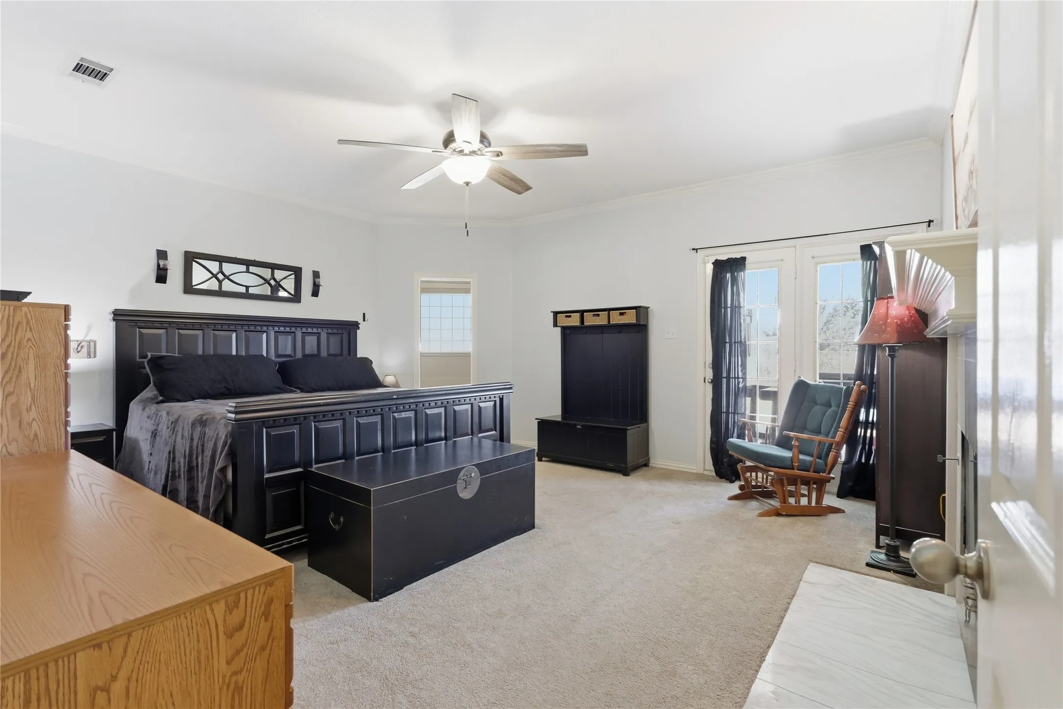 Recessed lighting, ceiling fan, neutral carpet, crown molding, and double French doors with transom windows