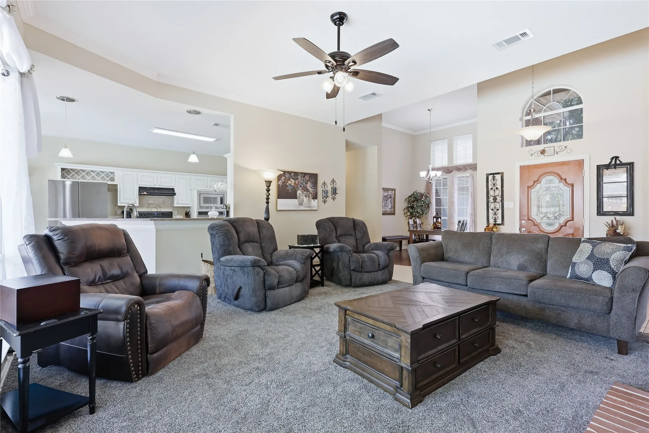 Living area with vaulted ceilings, ceiling fan, and arched window