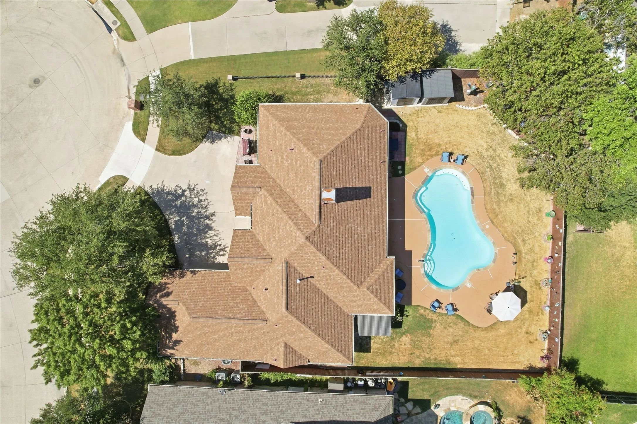 Spacious property featuring a large house with a shingle roof, a backyard swimming pool, and a storage shed