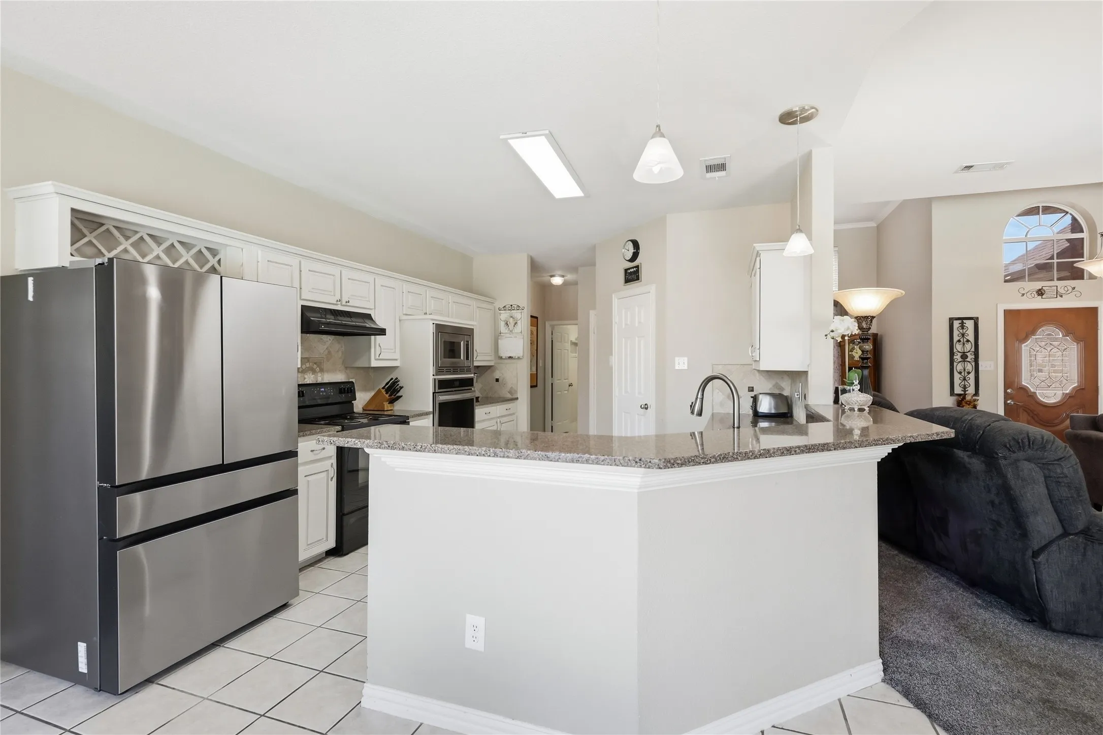 Kitchen featuring white cabinetry, built-in wine storage, stainless steel appliances, and a peninsula with a stone countertop