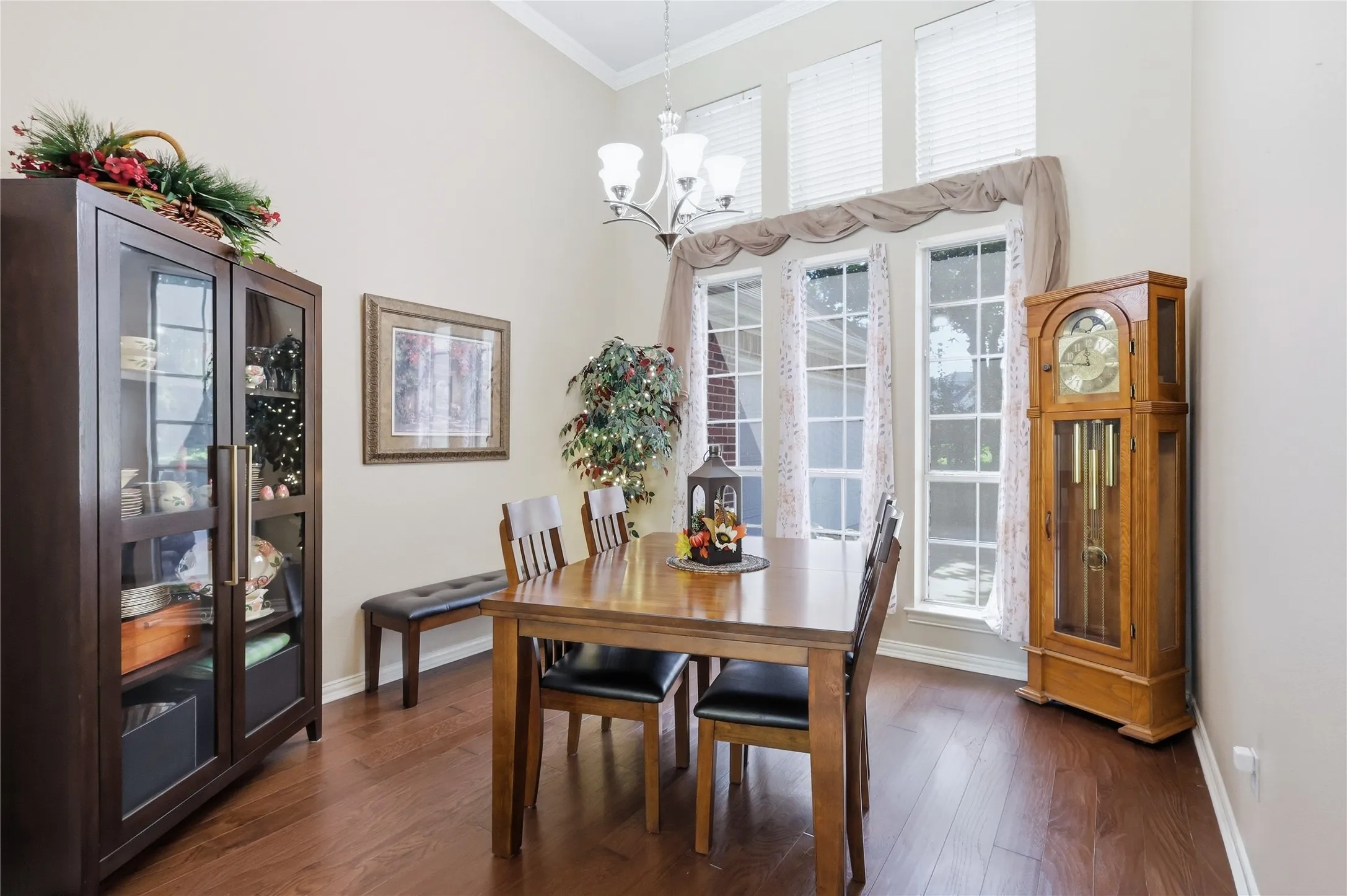Vaulted ceiling with a chandelier, wood-finish flooring, and multiple tall windows