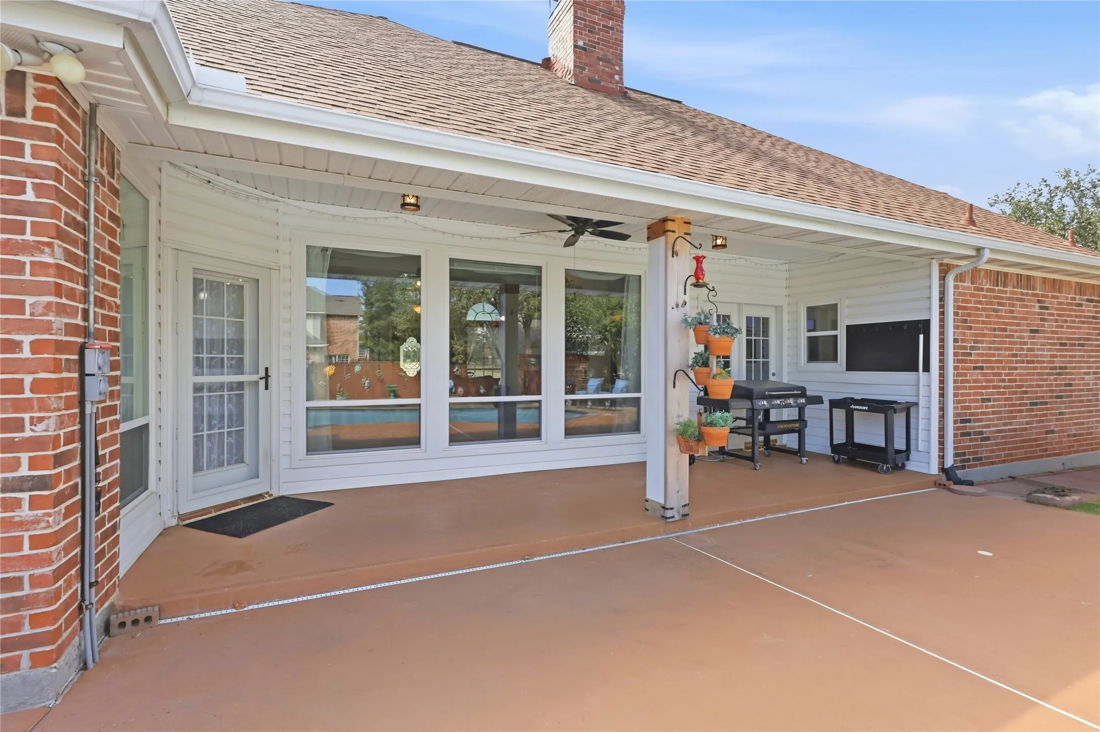 Covered patio with a ceiling fan, exterior lighting, and brick accents