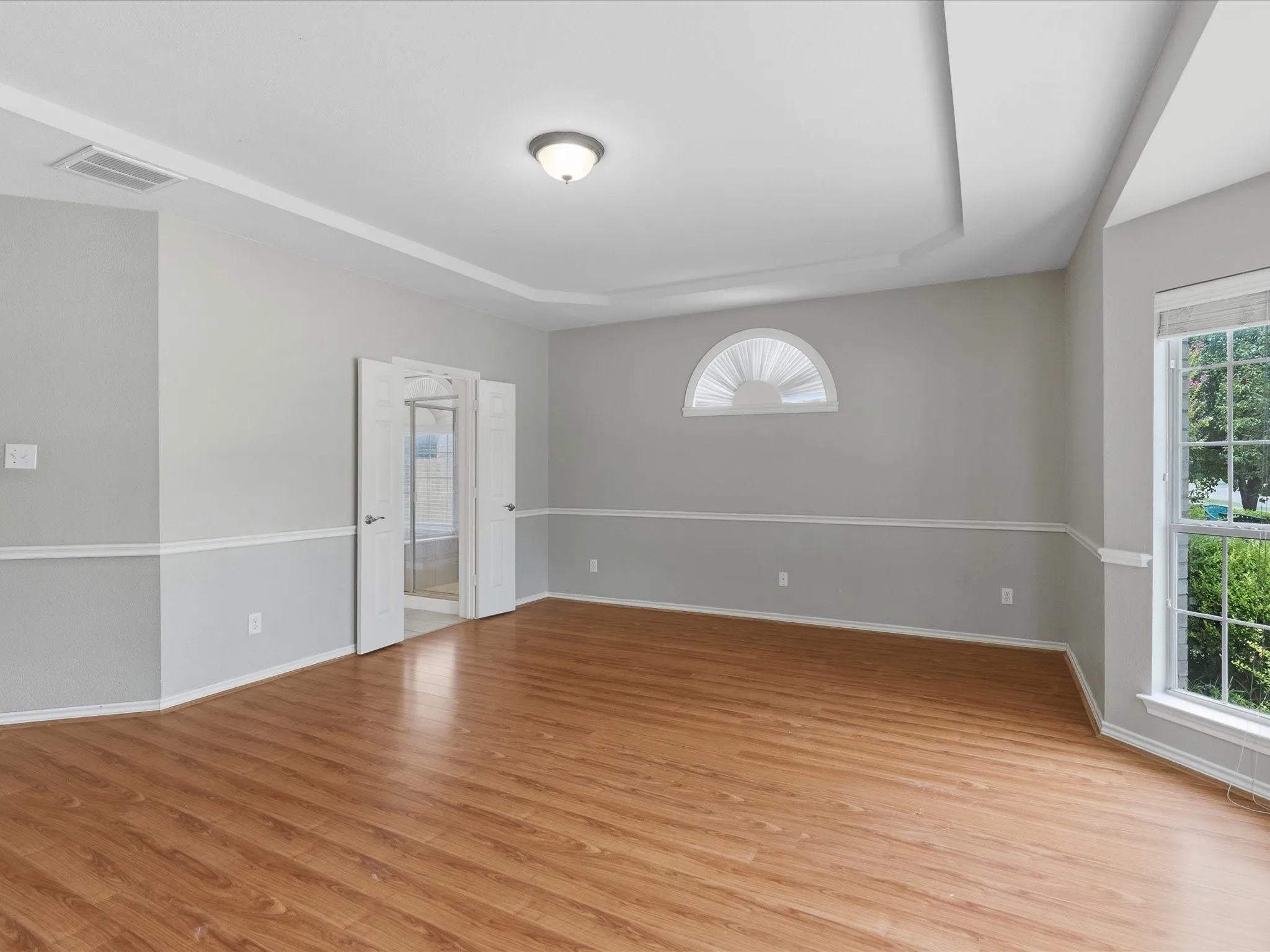 Recessed ceiling detail, wood-finish flooring, half-round transom window, chair rail molding, and a built-in overhead light fixture