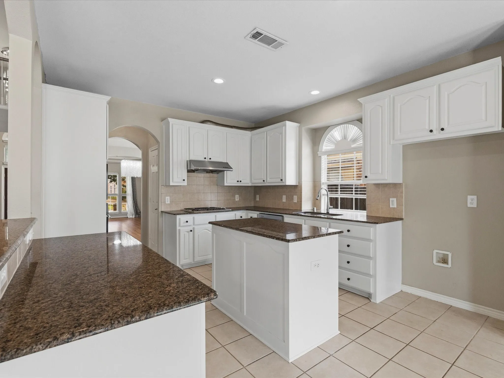 Kitchen featuring white cabinetry, a central island, tile flooring, and brown speckled countertops