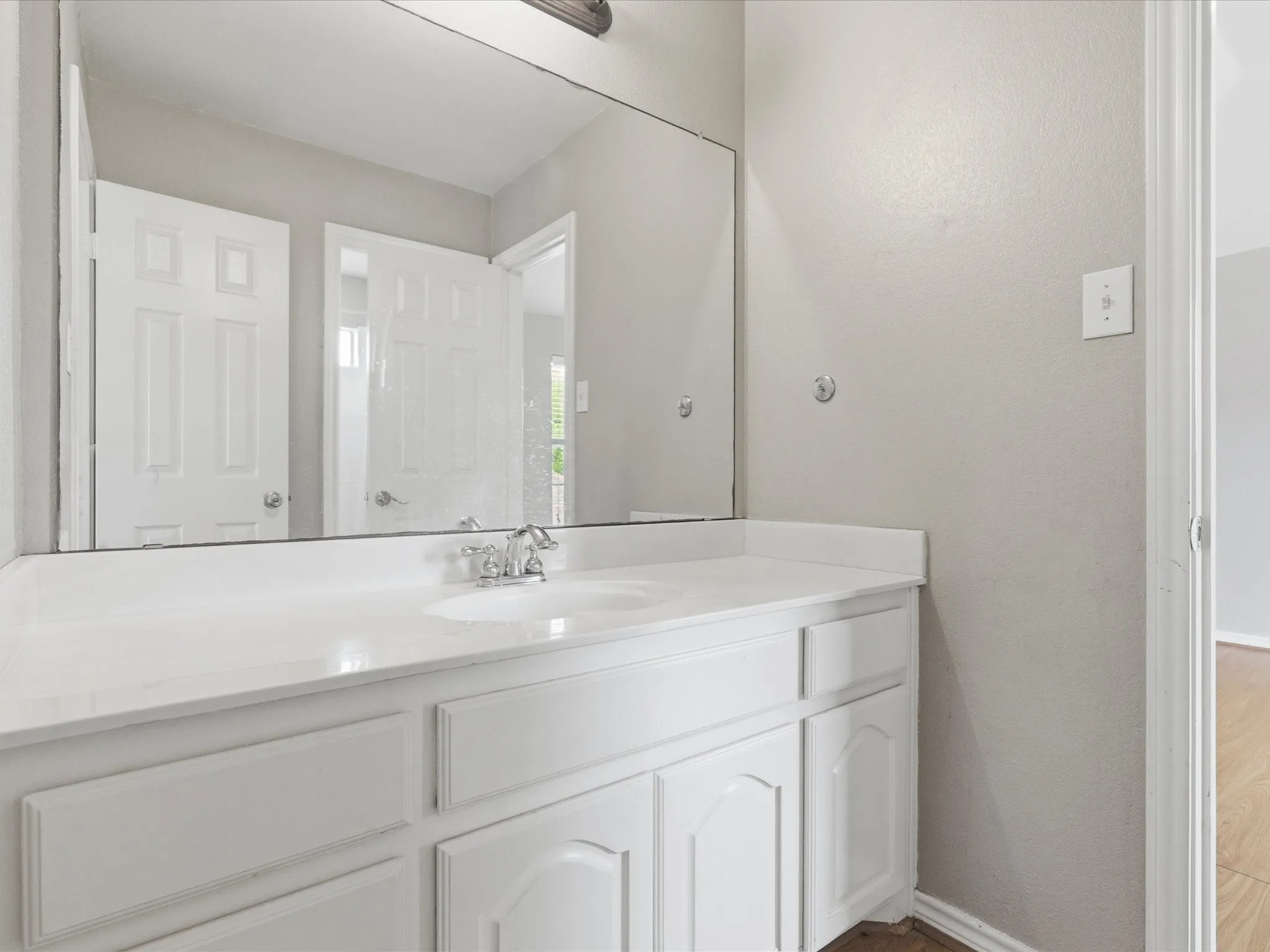 Bathroom vanity with a white countertop, undermount sink, chrome faucet, and integrated mirror