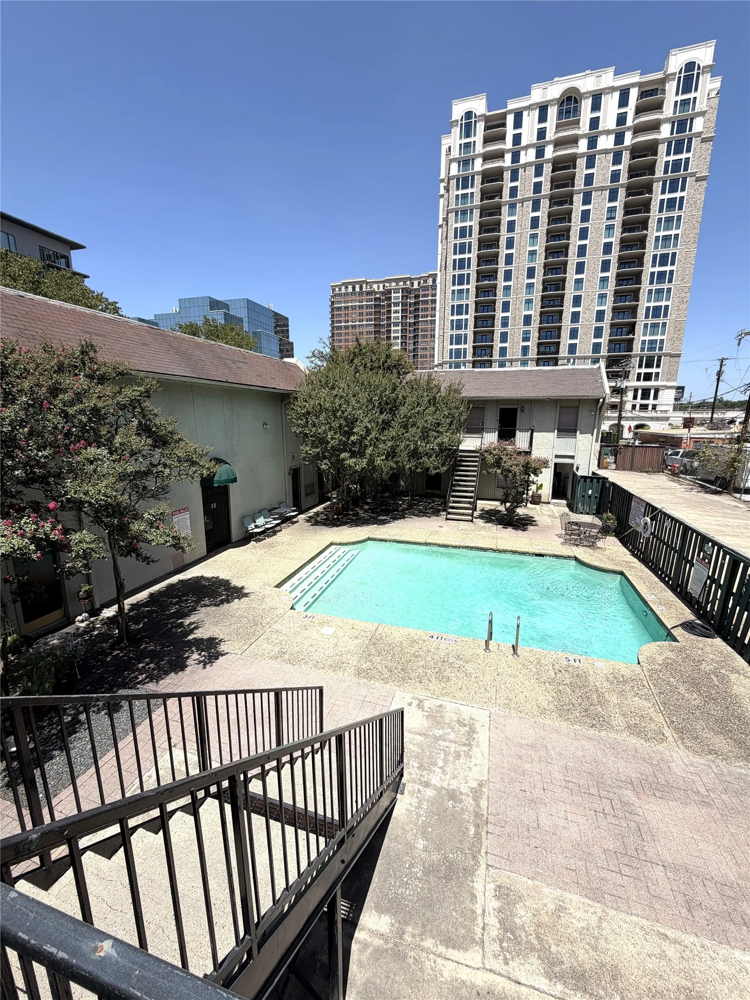 Outdoor swimming pool with integrated steps, surrounded by a stamped concrete deck and mature landscaping
