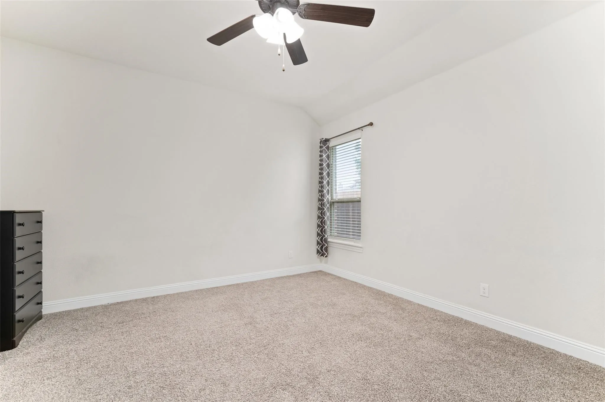 Expansive living area featuring wood-finish flooring, a corner fireplace with a white mantel, and a ceiling fan