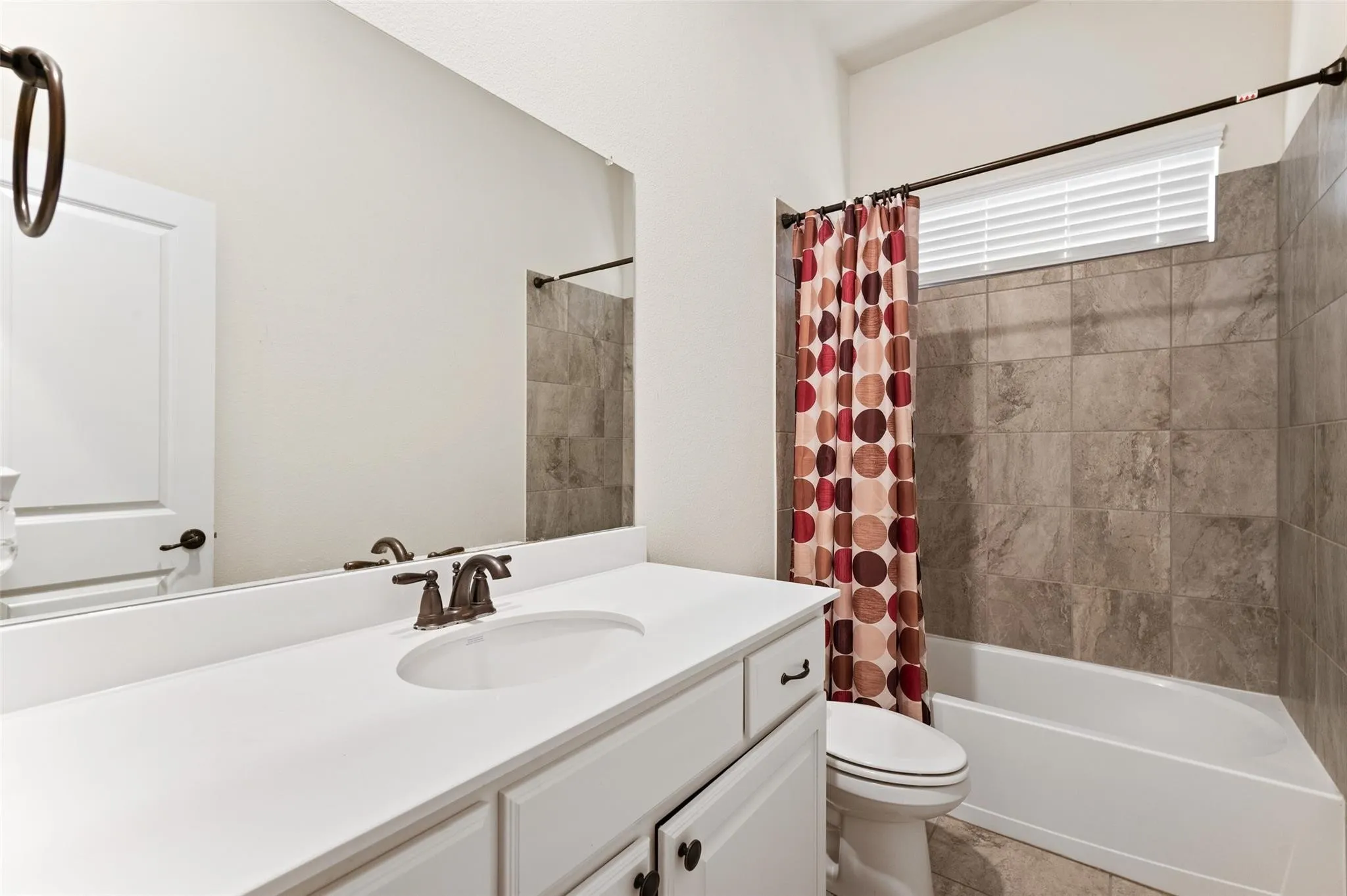 Recessed window with blinds and patterned drapes, ceiling fan with light fixture, light-toned carpet flooring, and white painted walls