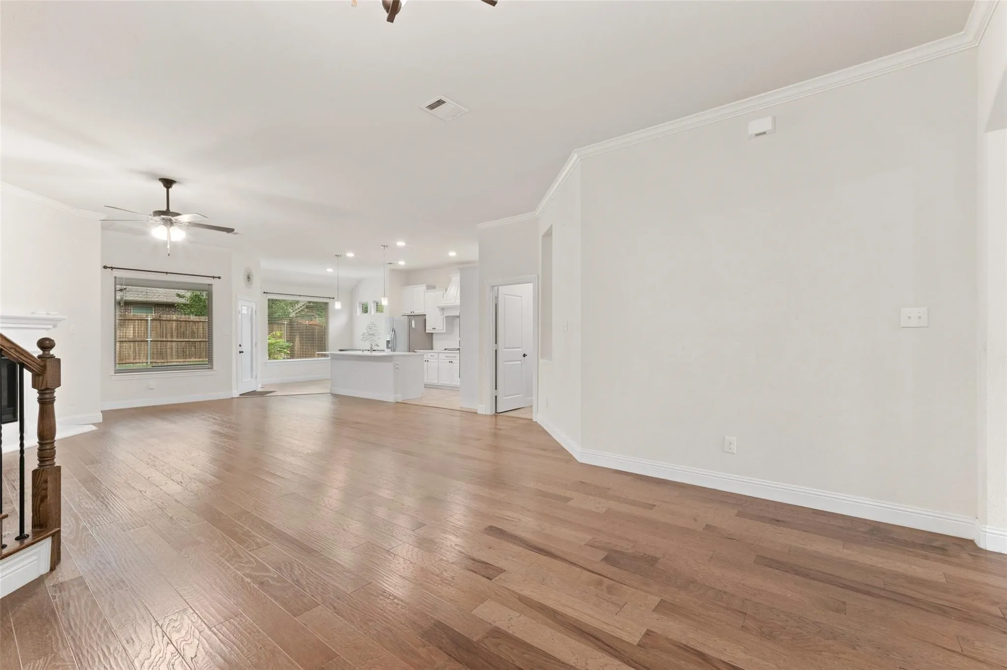 Arched window with blinds, wood-finish flooring, bi-fold closet doors, and a ceiling fan