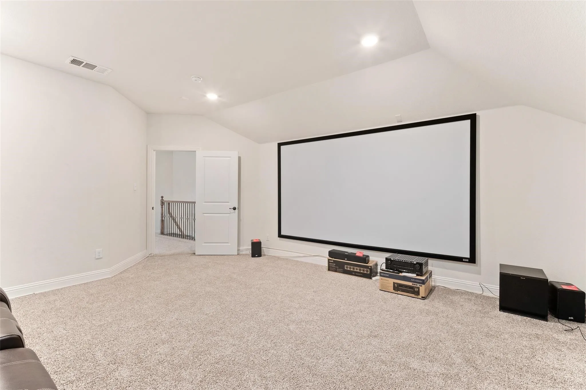 Spacious room featuring a large projector screen, recessed lighting, and sloped ceilings