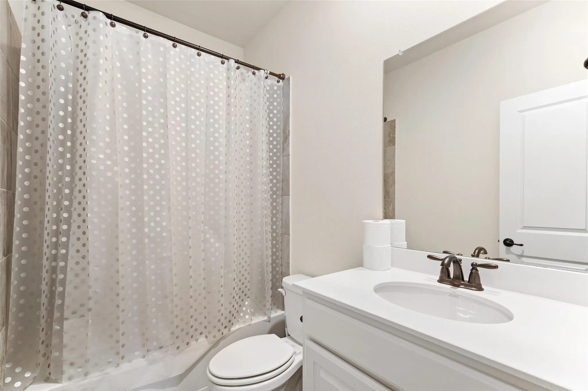 Bathroom featuring a built-in vanity with a white countertop and undermount sink, a bronze-finish faucet, and a framed mirror