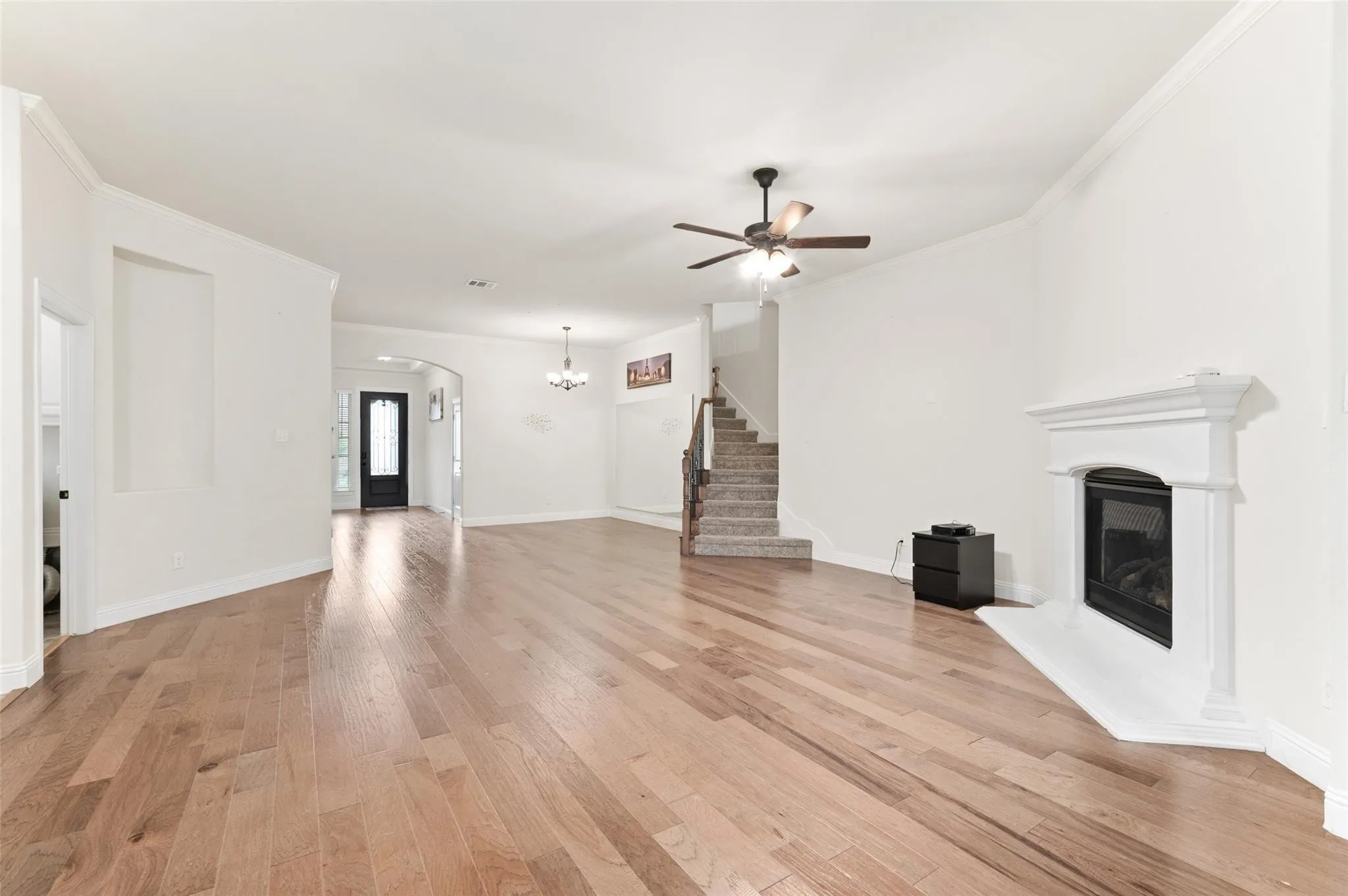 Wood-finish flooring throughout, white crown molding, and a ceiling fan