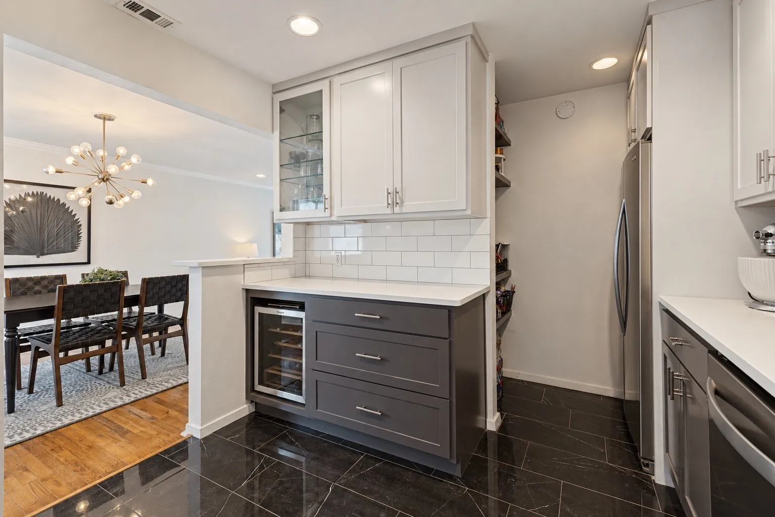 Kitchen featuring black tile flooring, white subway tile backsplash, white countertops, two-tone cabinetry, and a built-in wine refrigerator