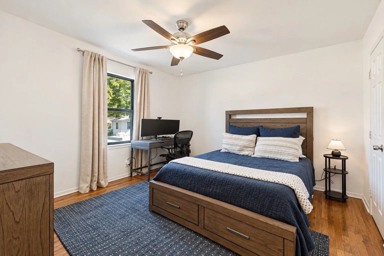 Hardwood flooring, ceiling fan with integrated lighting, white paneled door, and a window providing natural light